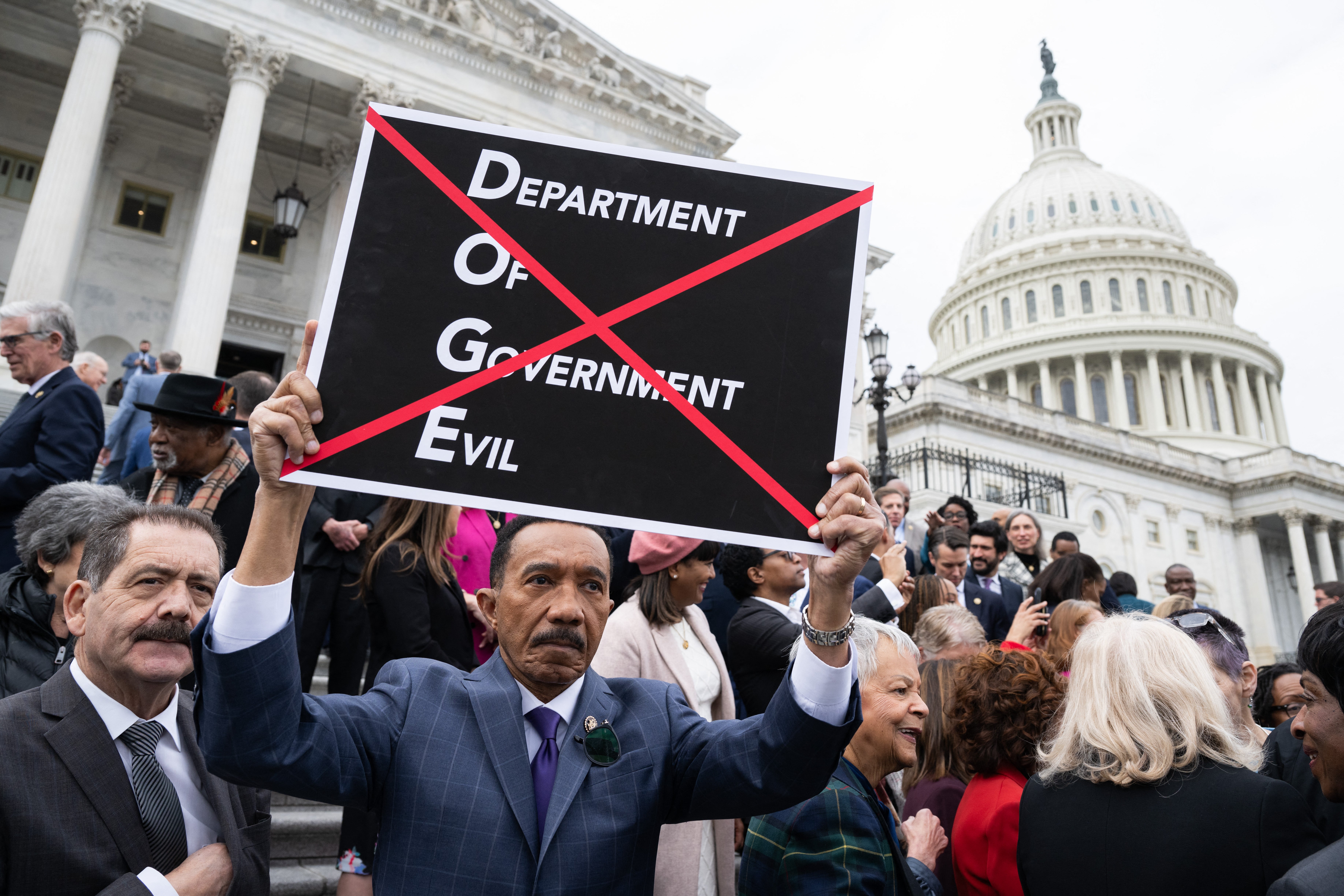 Democratic U.S. Rep. Kweisi Mfume holds a sign against DOGE during a press conference against a House Republican budget bill on February 25