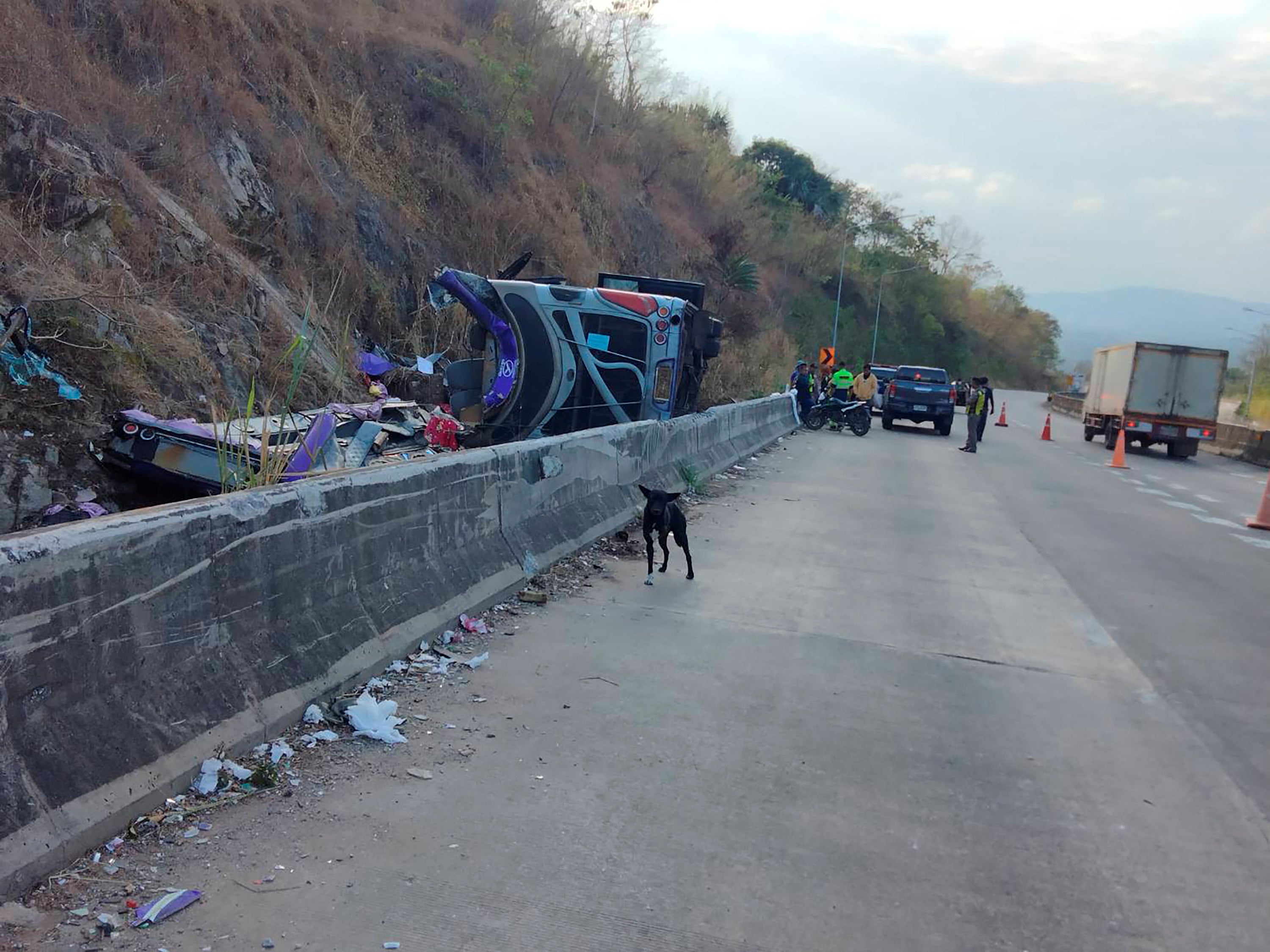 An overturned bus is pictured after losing control and falling into a ditch during its journey from Bueng Kan to Rayong, resulting in several deaths