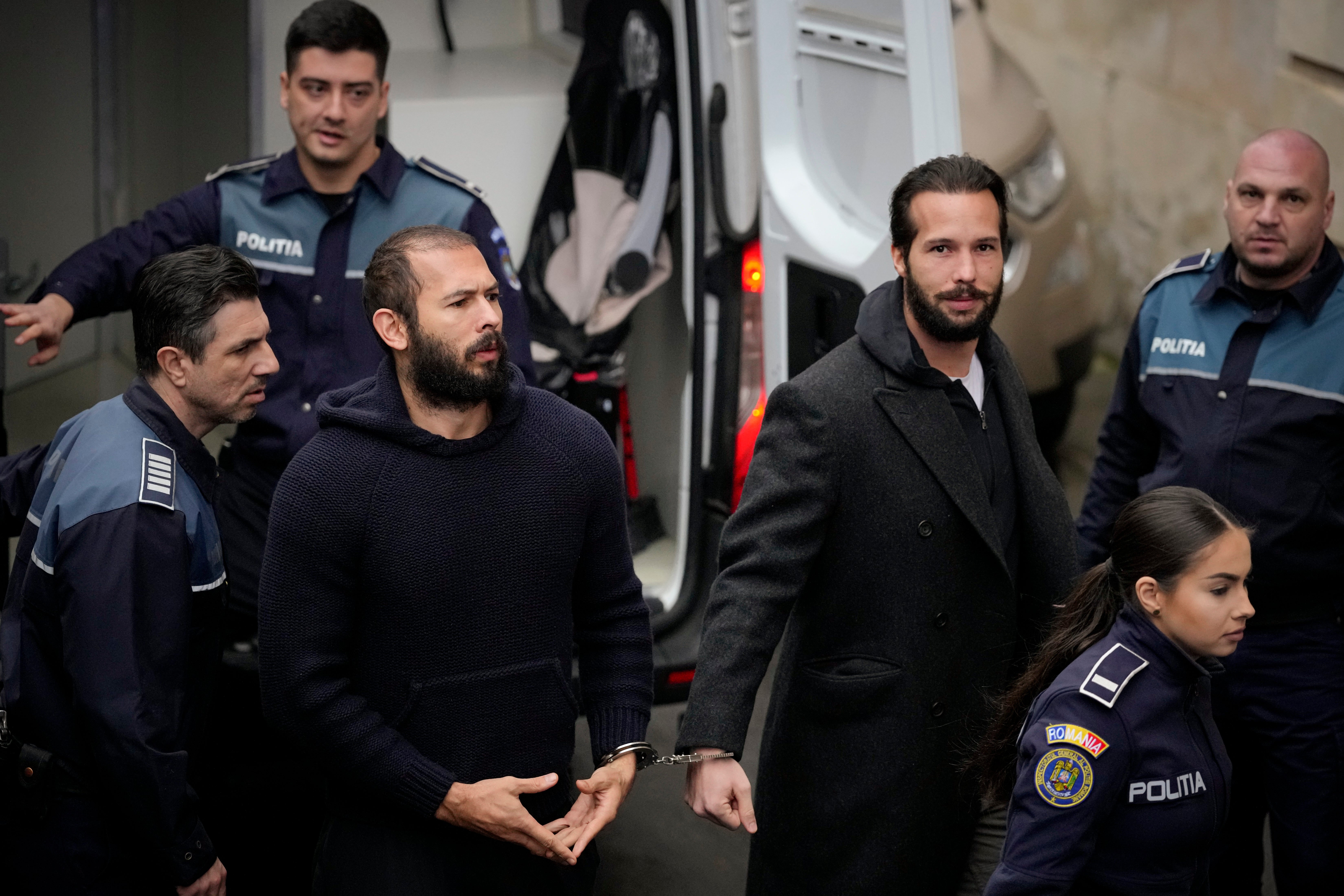 Police officers escort Andrew Tate, center, and brother Tristan to the Court of Appeal in Romania in February 2023