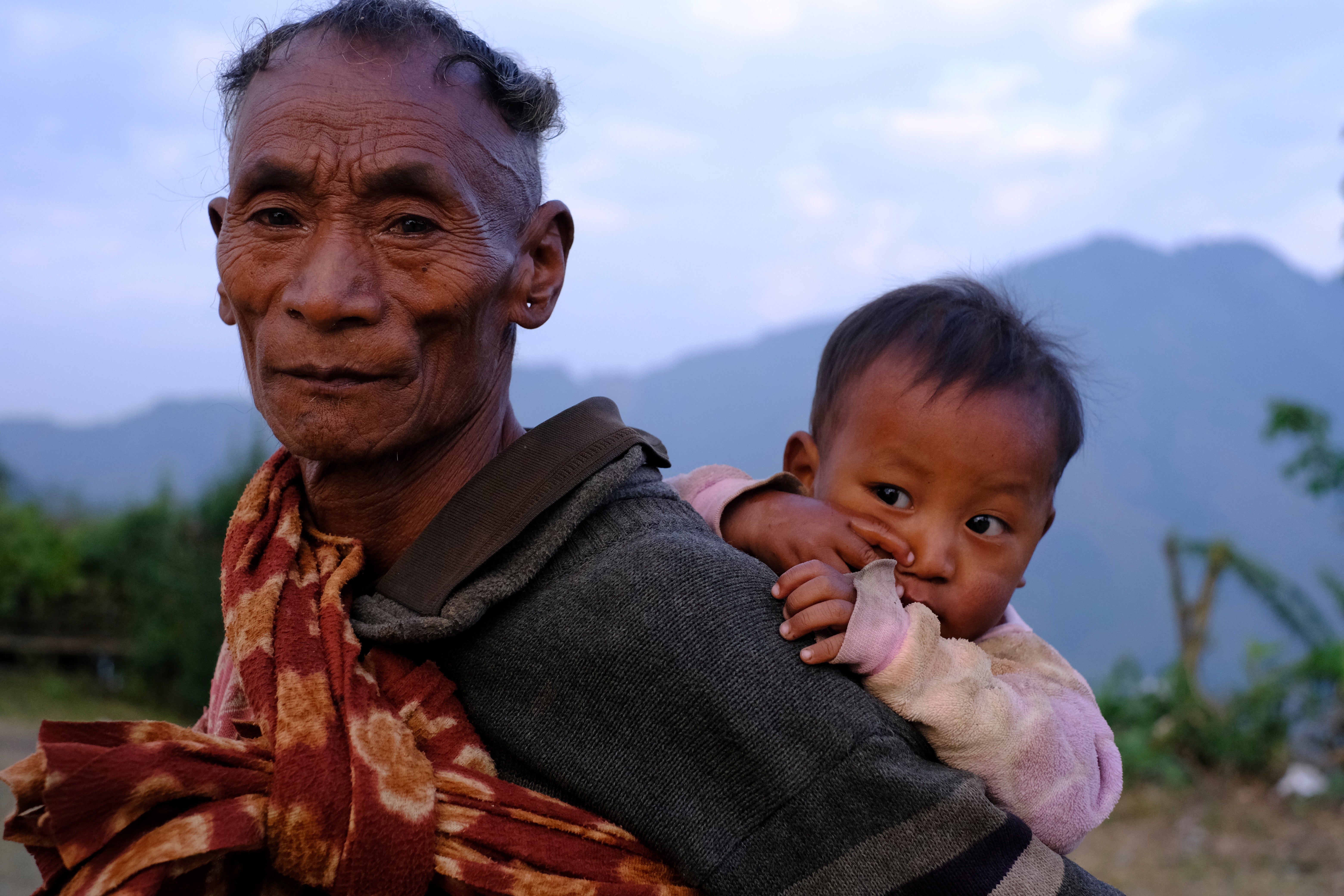 A Konyak Naga carries a child in Longwa