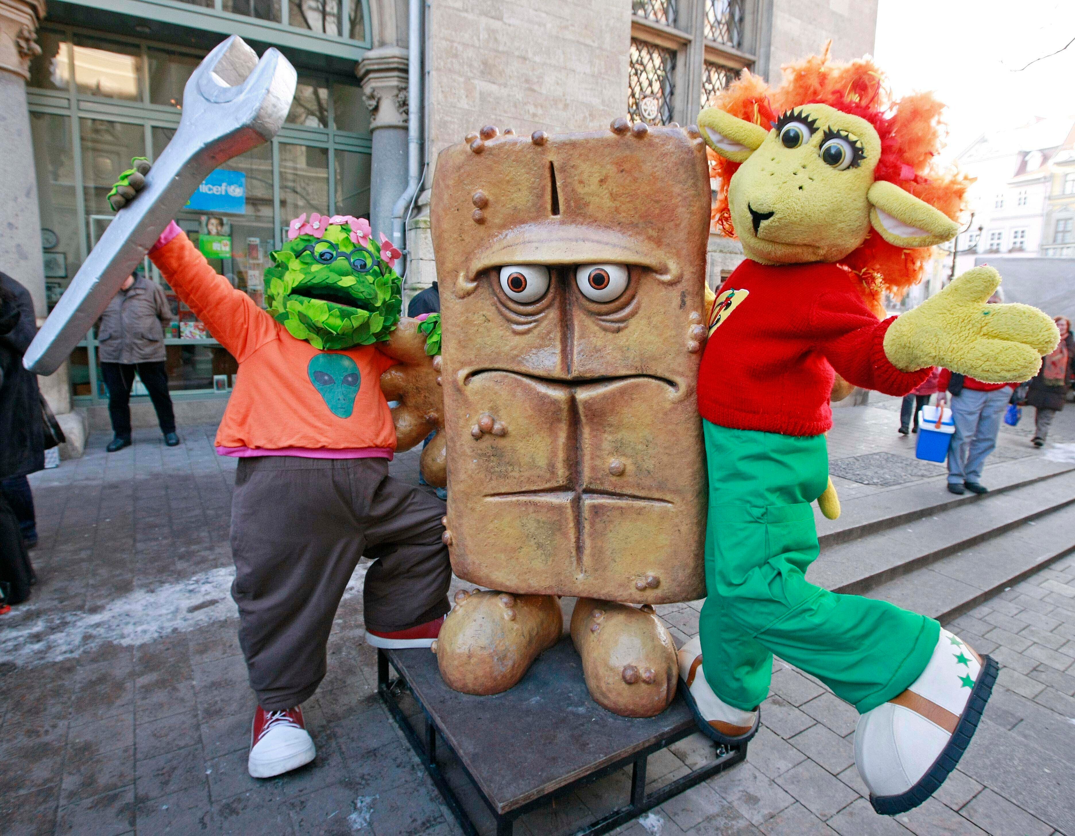 The puppet characters on the German children's television channel 'Kika' 'Briegel der Busch', left, and 'Chilie das Schaf', right, present the statue ‘Bernd das Brot’ at his regular place in front of the City hall in Erfurt