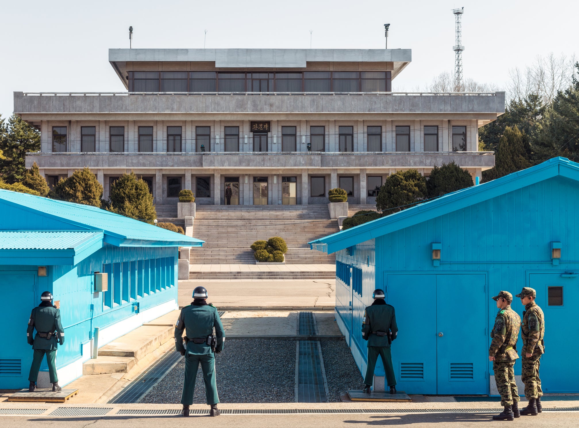 <p>Soldiers facing each other across the border between North Korea and South Korea, with South Korean soldiers in the foreground, and a North Korean soldier in the distance</p>