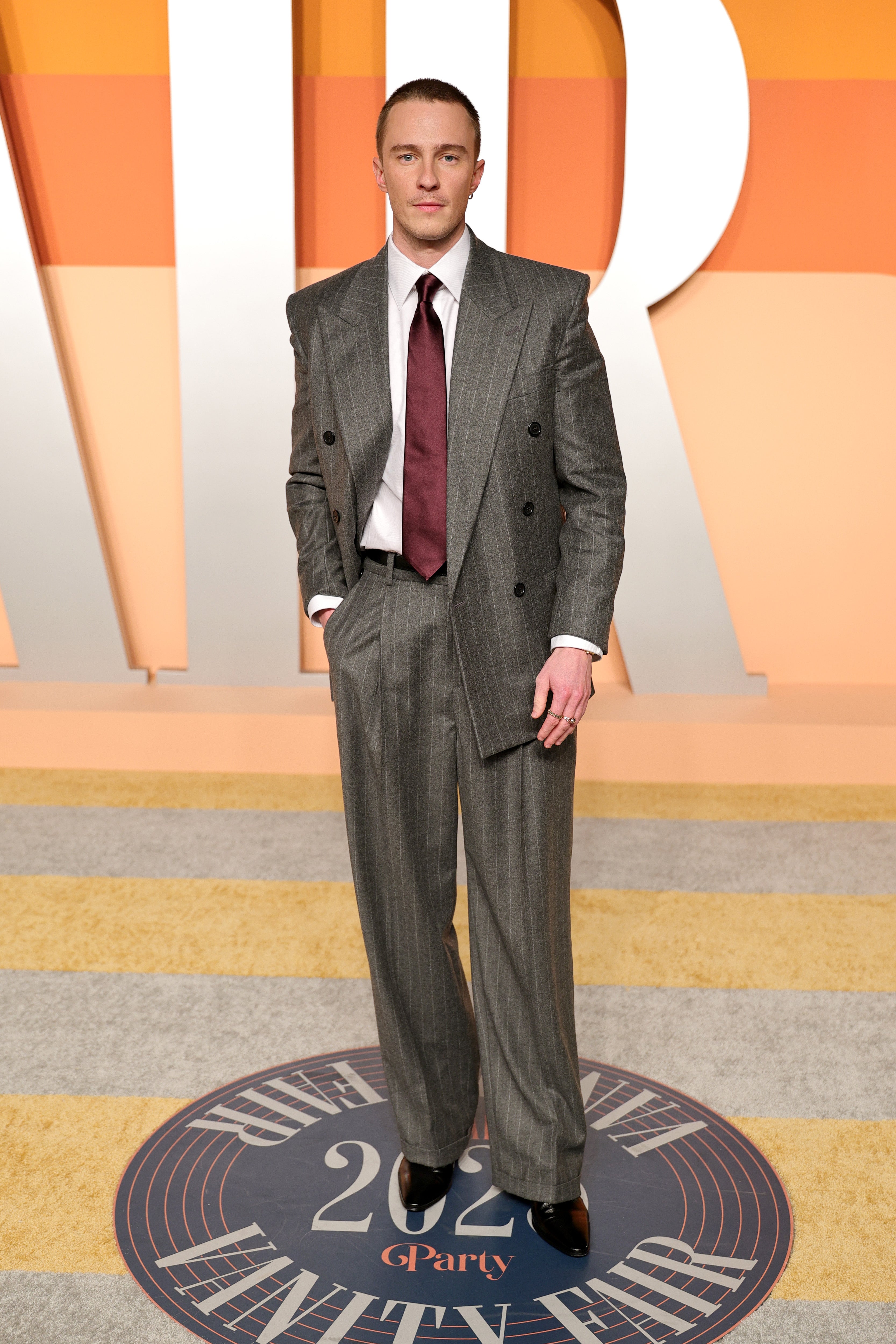 Drew Starkey opted for a double-breasted pinstripe suit with a satin maroon tie for the glamorous post-Oscars night out