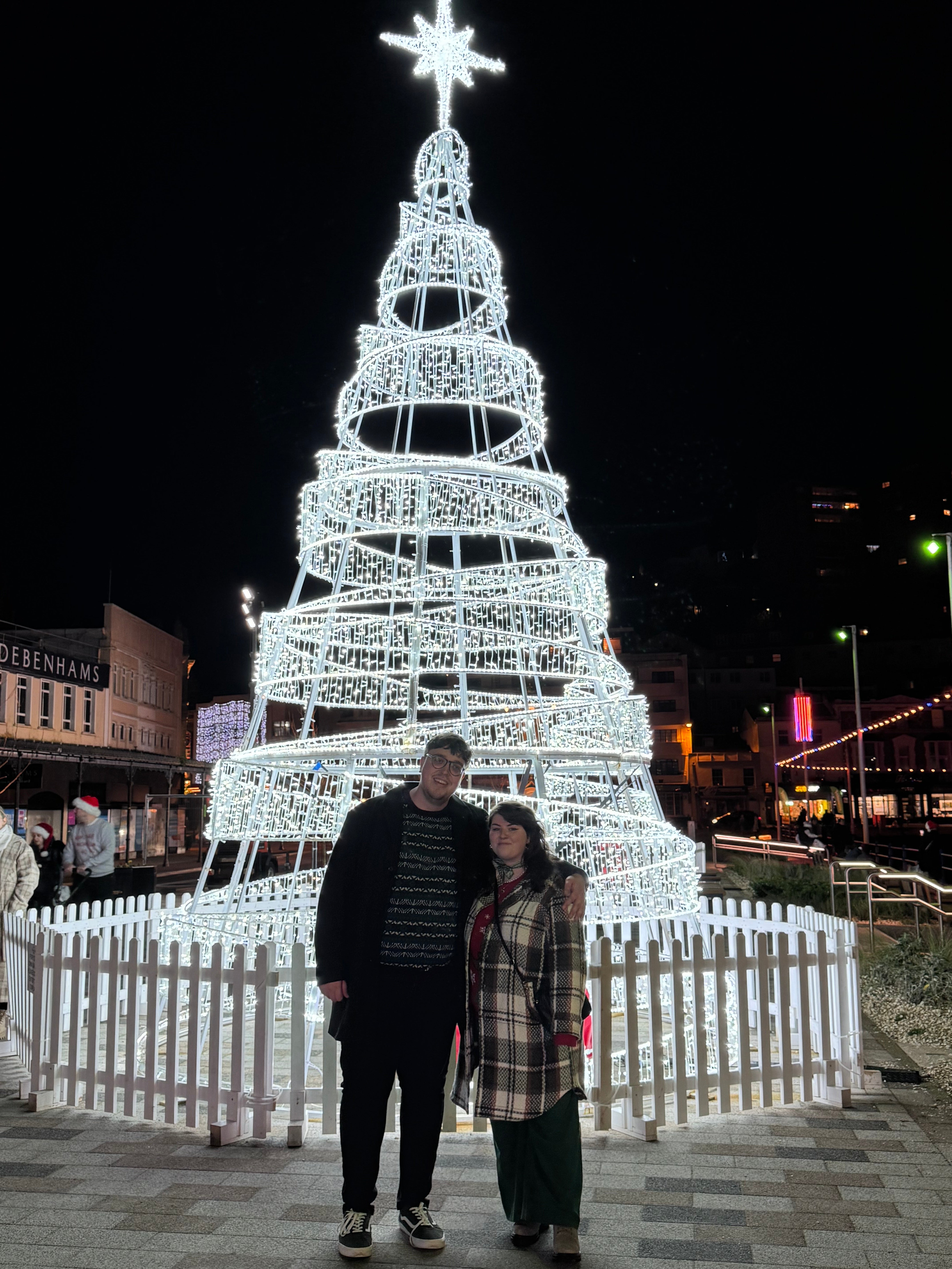 Nathaniel and Karin standing together in front of a white Christmas tree