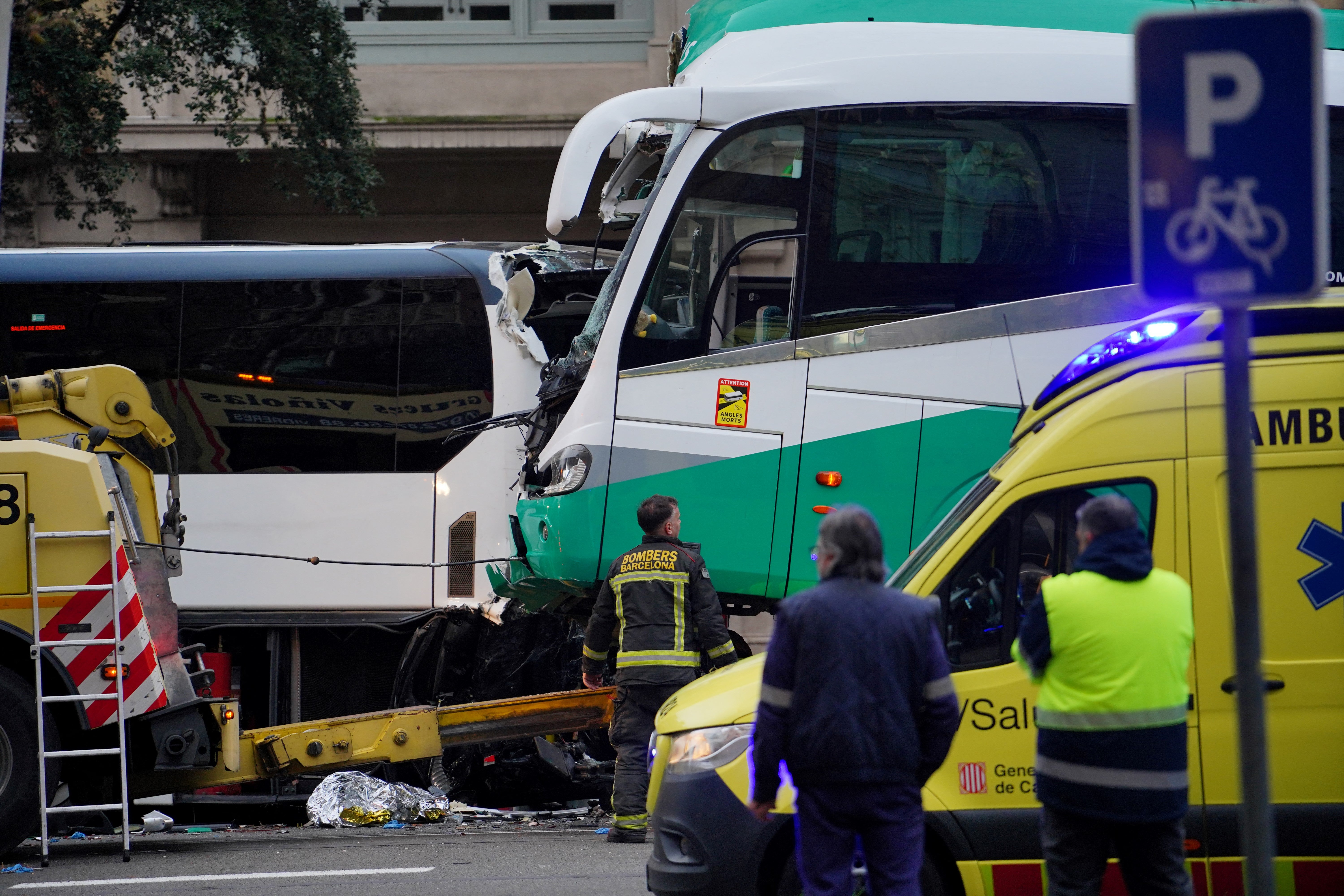 Firefighters and police officers stand next to a bus after two buses collided in Barcelona