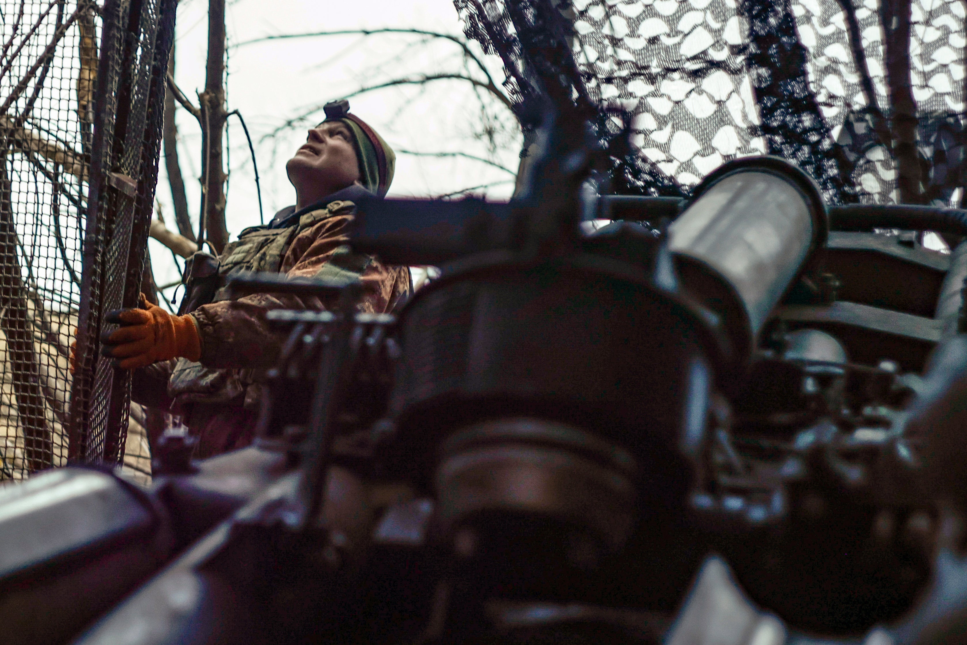 A Ukrainian soldier looks at the sky searching for Russian FPV drones as he gets ready to fire a M777 howitzer towards Russian positions at the frontline near Donetsk, March 3, 2025