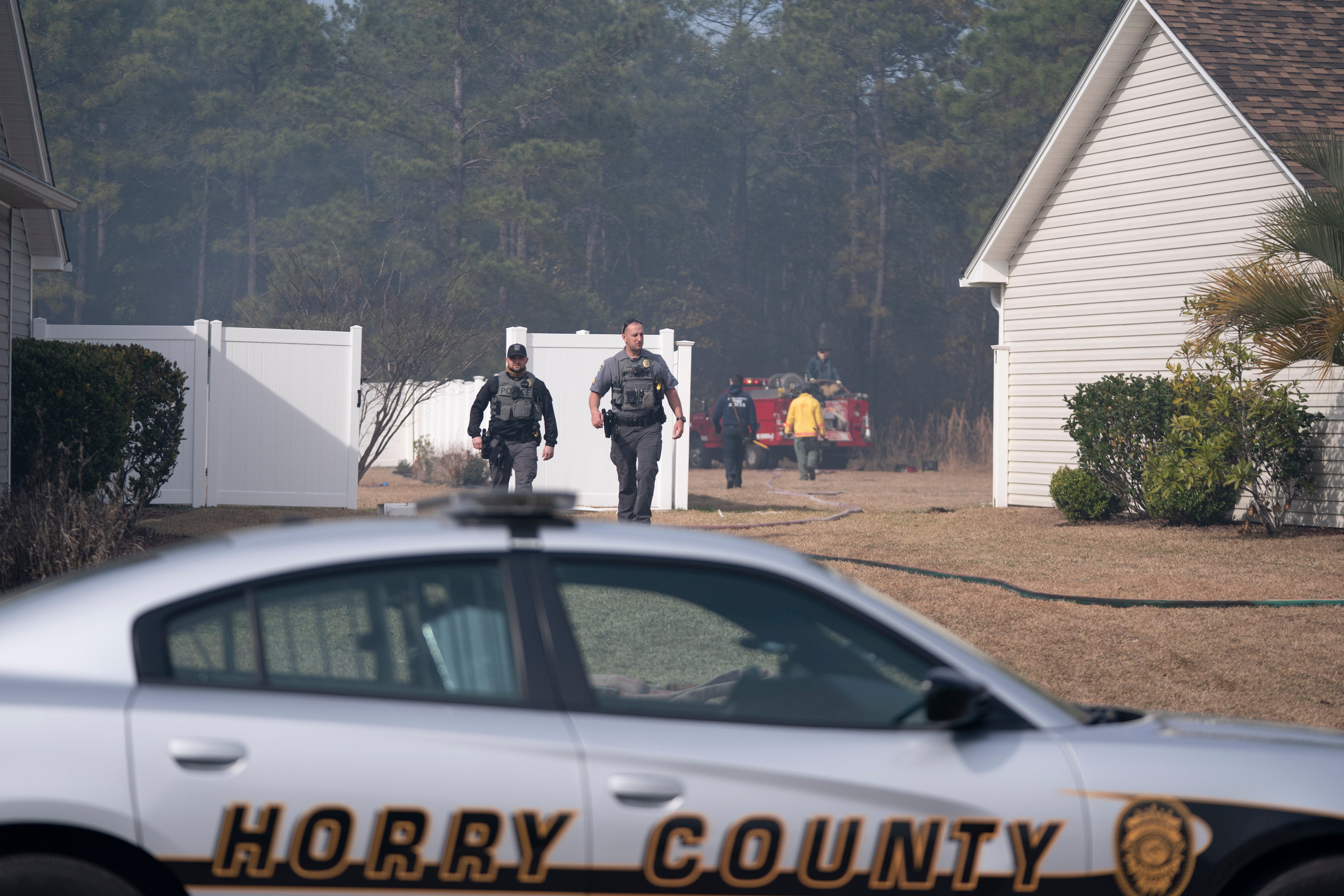 Membros da aplicação da lei voltam ao seu veículo enquanto os bombeiros combatem um surto no bairro de Carolina Forest em 2 de março de 2025 em Myrtle Beach, Carolina do Sul