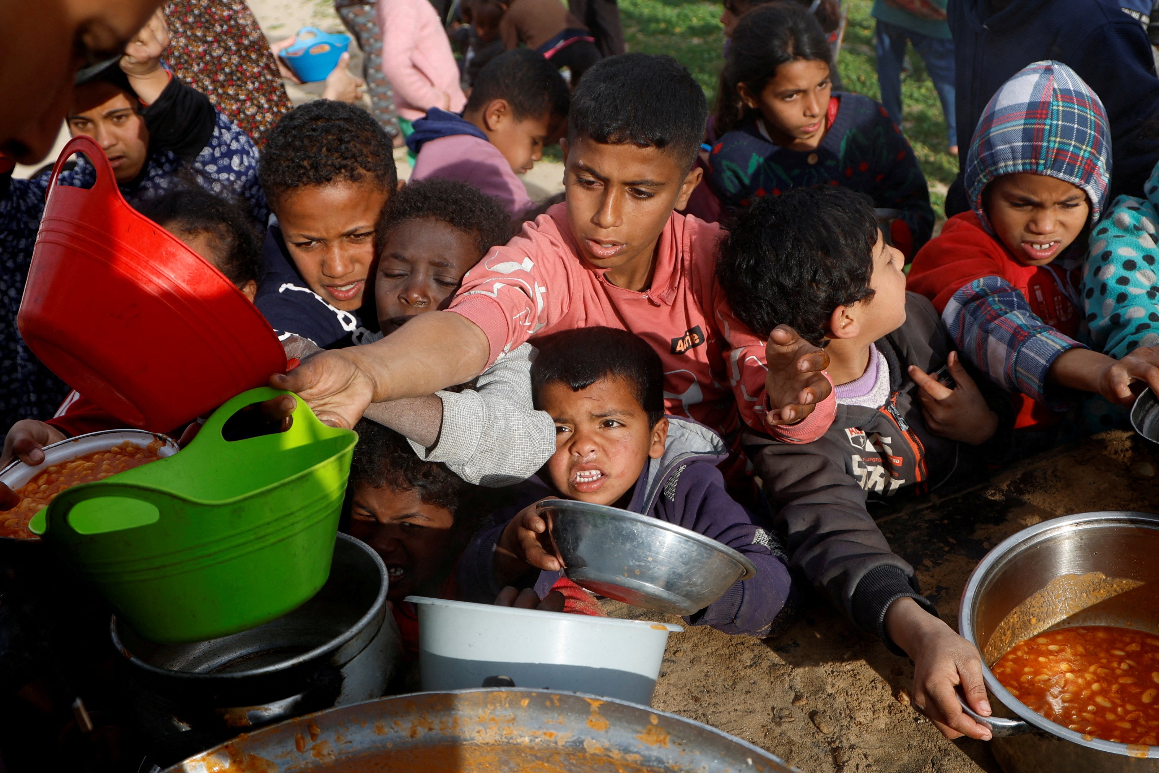 Palestinian children gather to receive food cooked by a charity kitchen, during the Muslim holy month of Ramadan, in Khan Younis, in the southern Gaza Strip, M