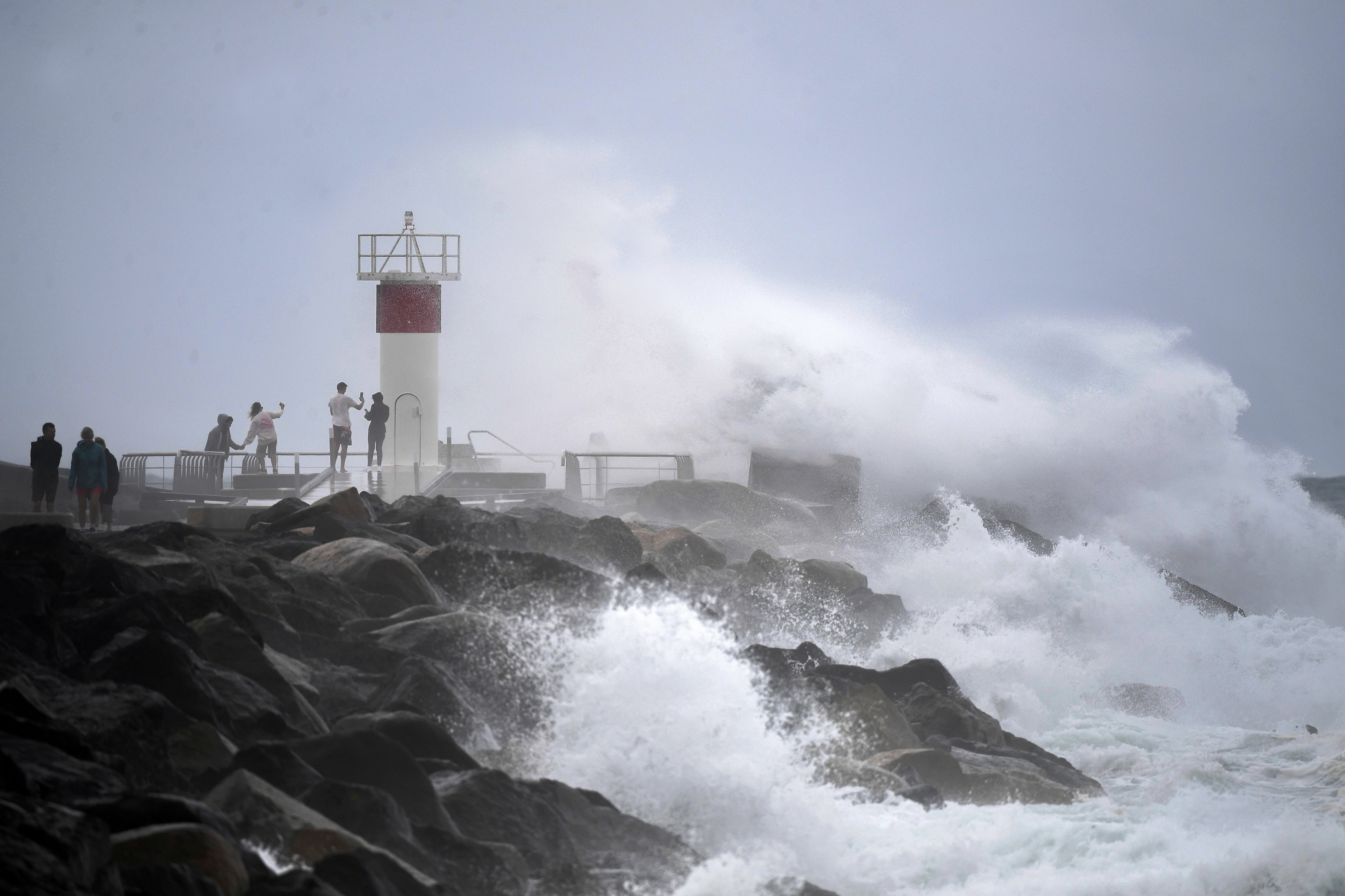 Waves crash onto rocks as people look on at the Spit, on the Seaway on the Gold Coast, Australia, Monday, 3 March as Cyclone Alfred builds off the east coast