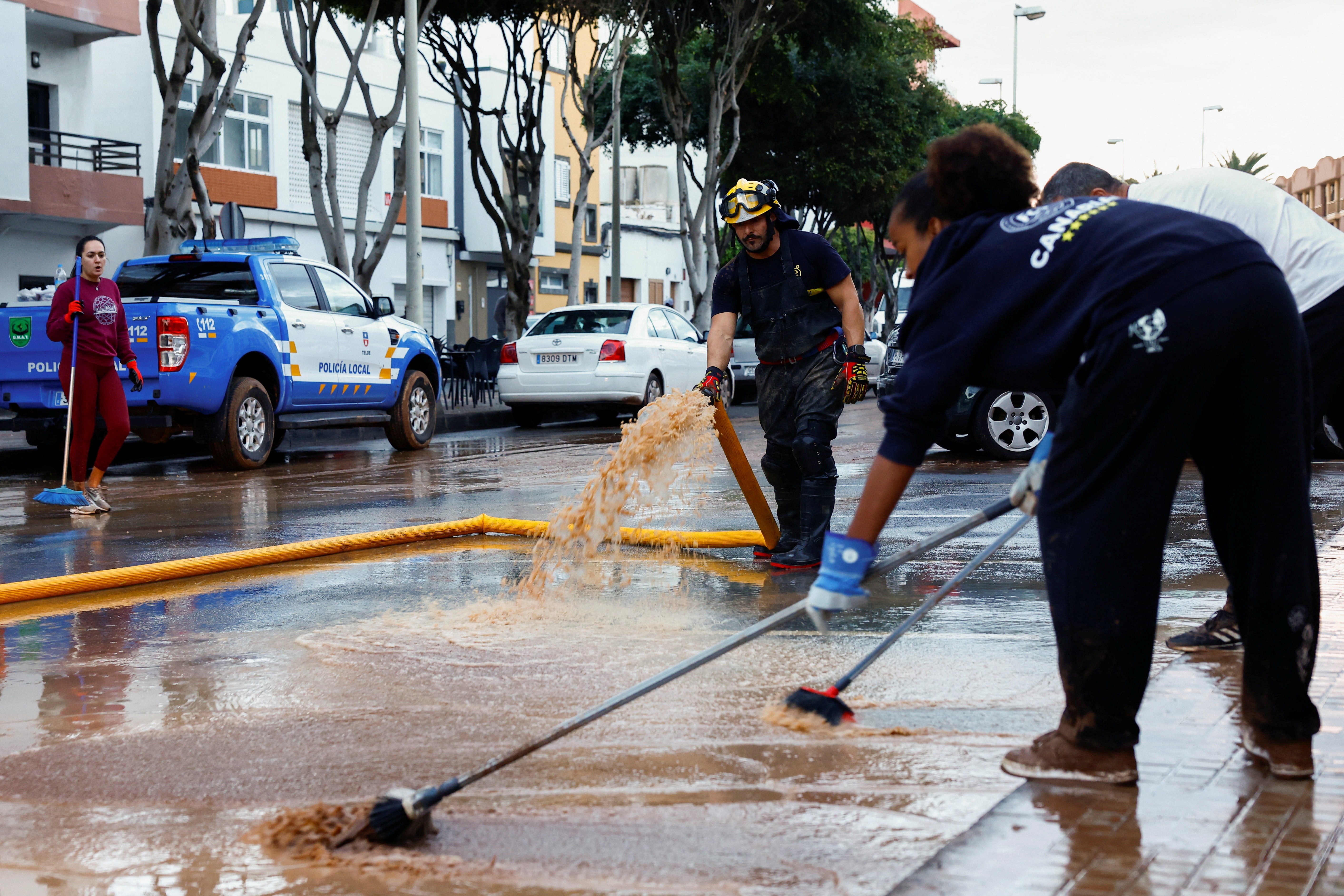 People clean mud with the help of a firefighter in the Salinetas neighbourhood in Telde