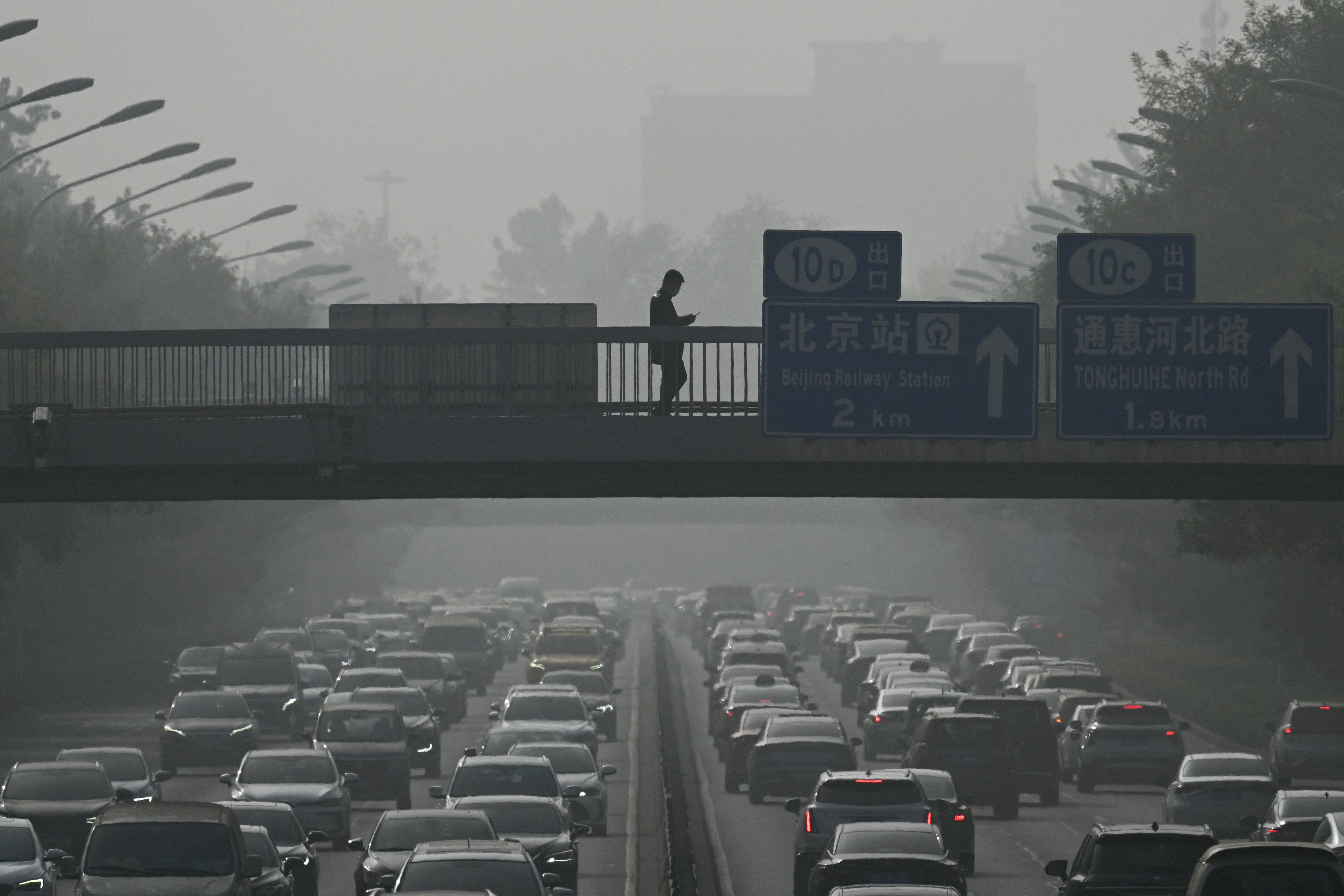 Pedestrians walk on an overpass as traffic snarls amid haze from air pollution in Beijing in 2023. The State Department is shutting down a worldwide U.S. air quality monitoring program that helped improve air quality in China.