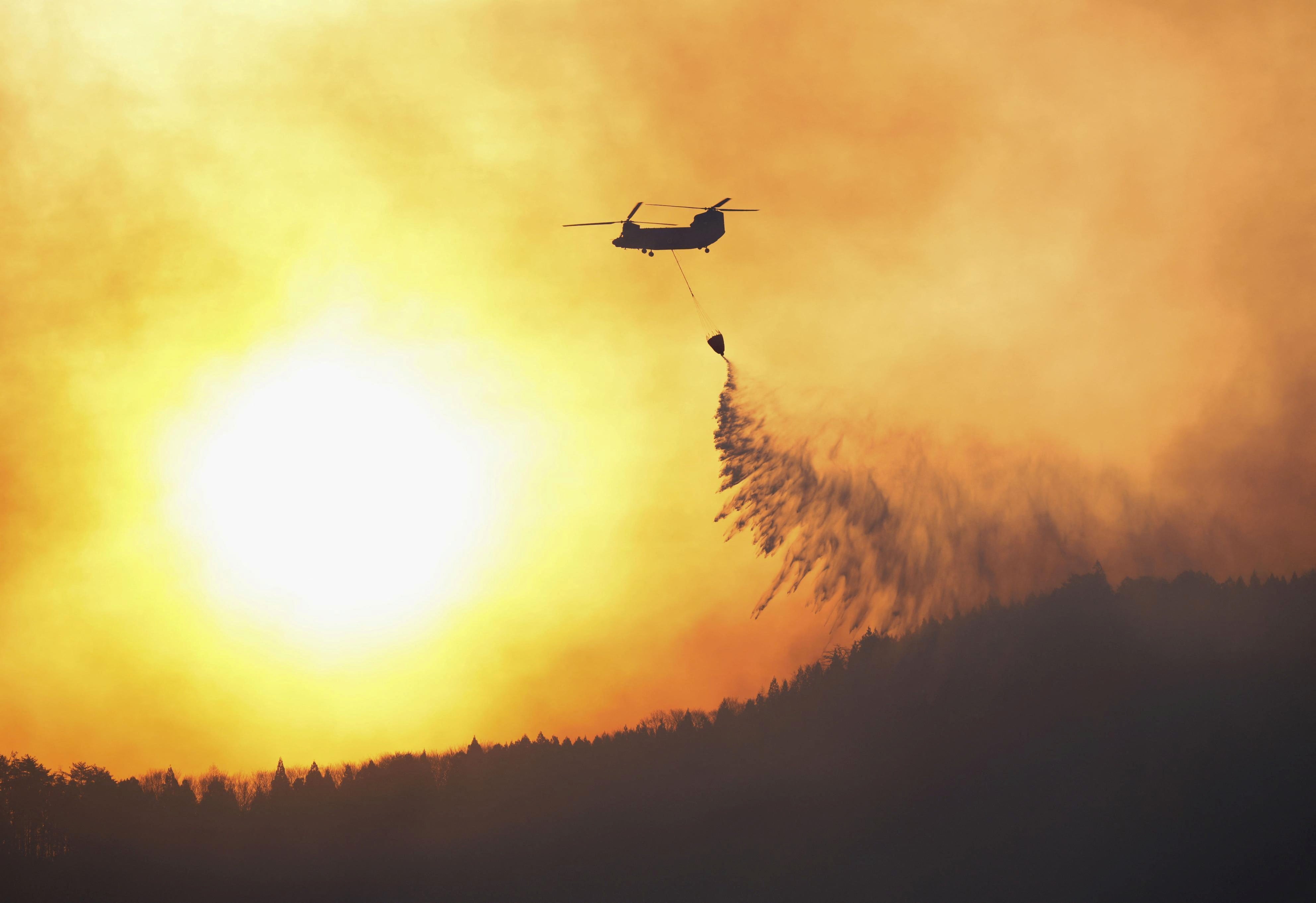 A Japanese helicopter self-defense power leads fire fighting operations from the air at a forest fire location in Ofunato, Iwate Prefecture