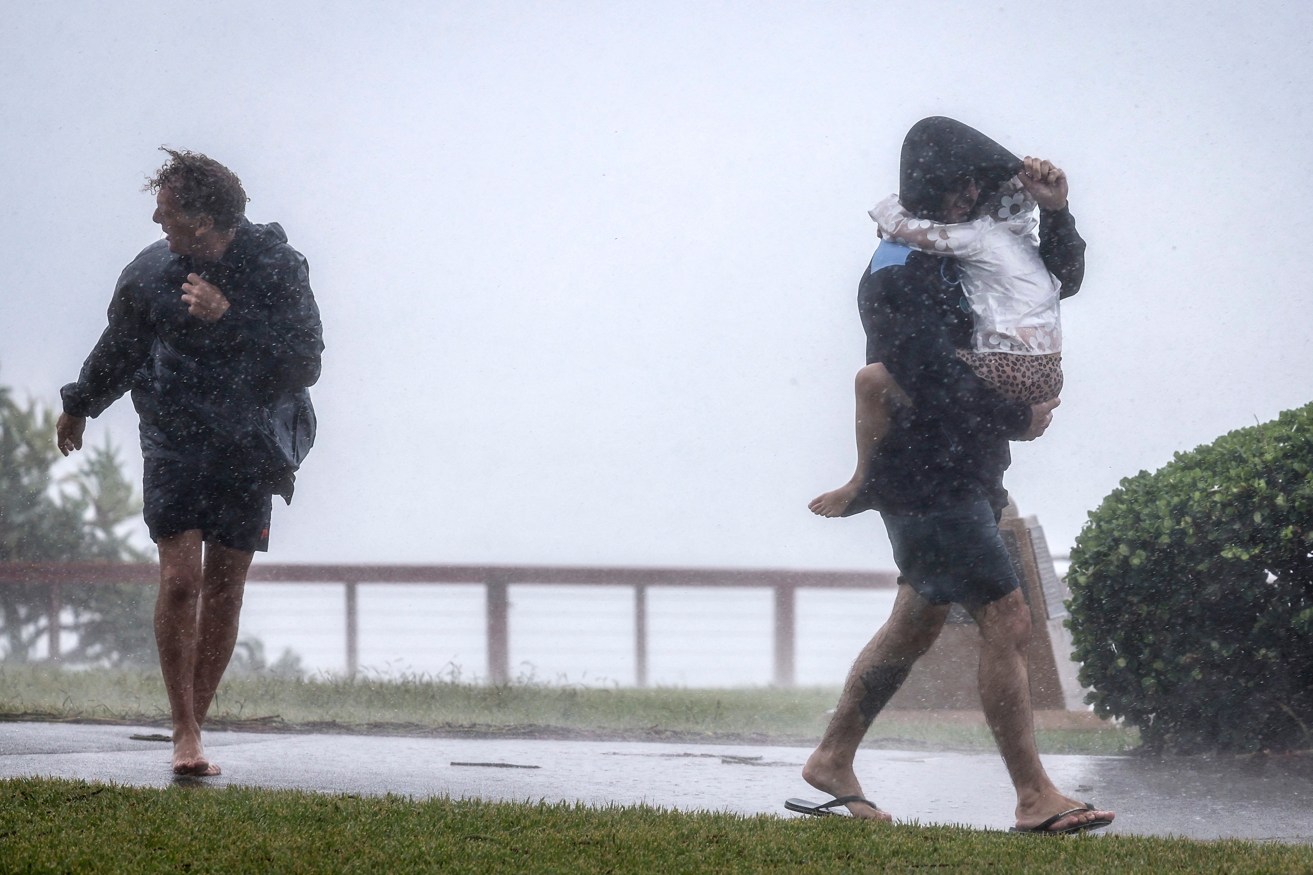 People walk through heavy rain and wind as the outer fringe of Tropical Cyclone Alfred started whipping eastern Australia