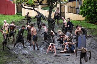 Boys and girls slide down the side of a muddy hill at Miami Beach, along the southern end of the Gold Coast