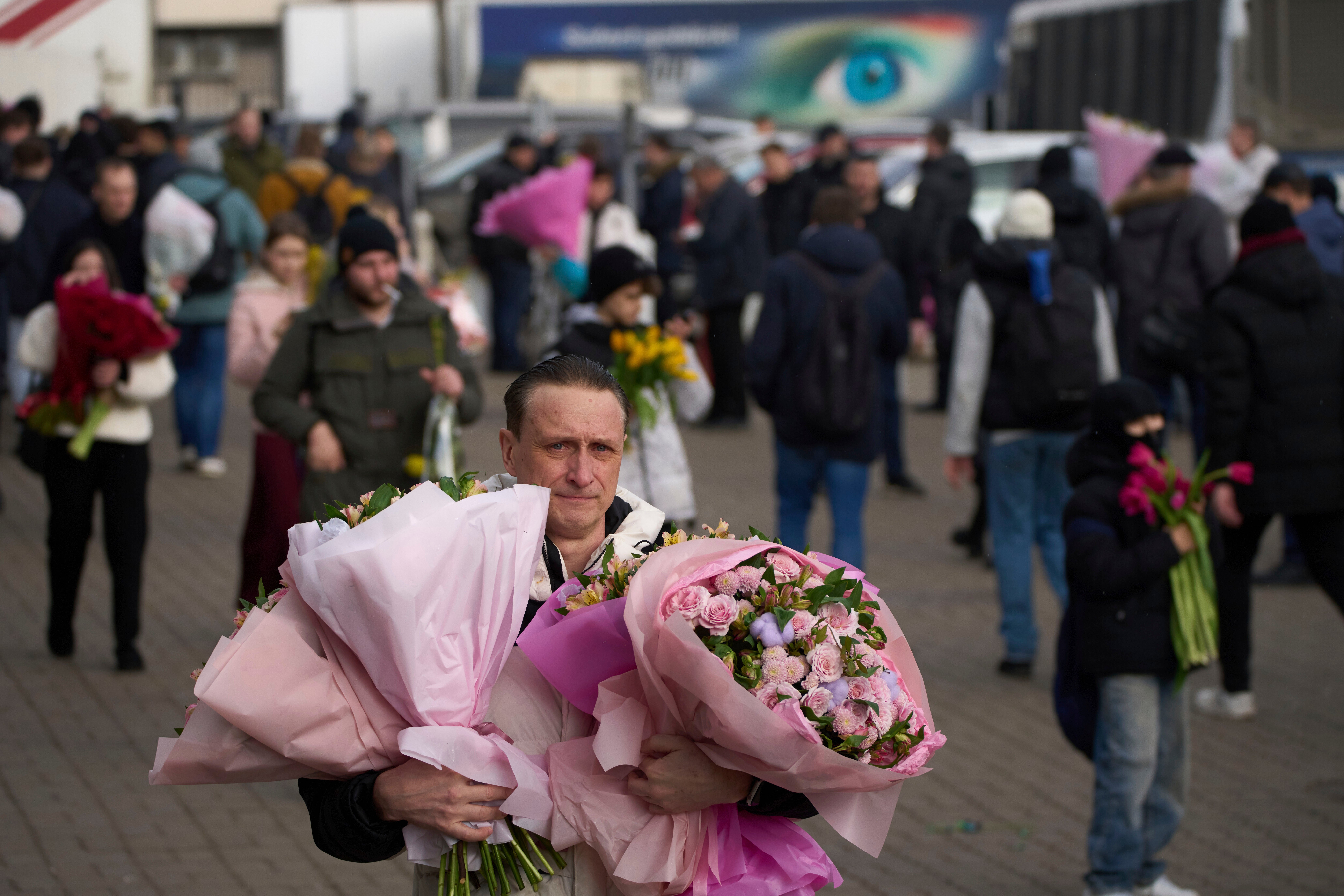 A man carries bars of flowers purchased from the flower market on the eve of a world female day in Moscow