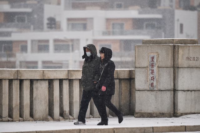 <p>People walk on the bridge of Pothong Gate as it snows in Pyongyang </p>