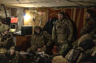 Soldiers wait for coordinates in a garage as they prepare to fire an American-supplied M101 howitzer on Russian combat positions in the Kharkiv region