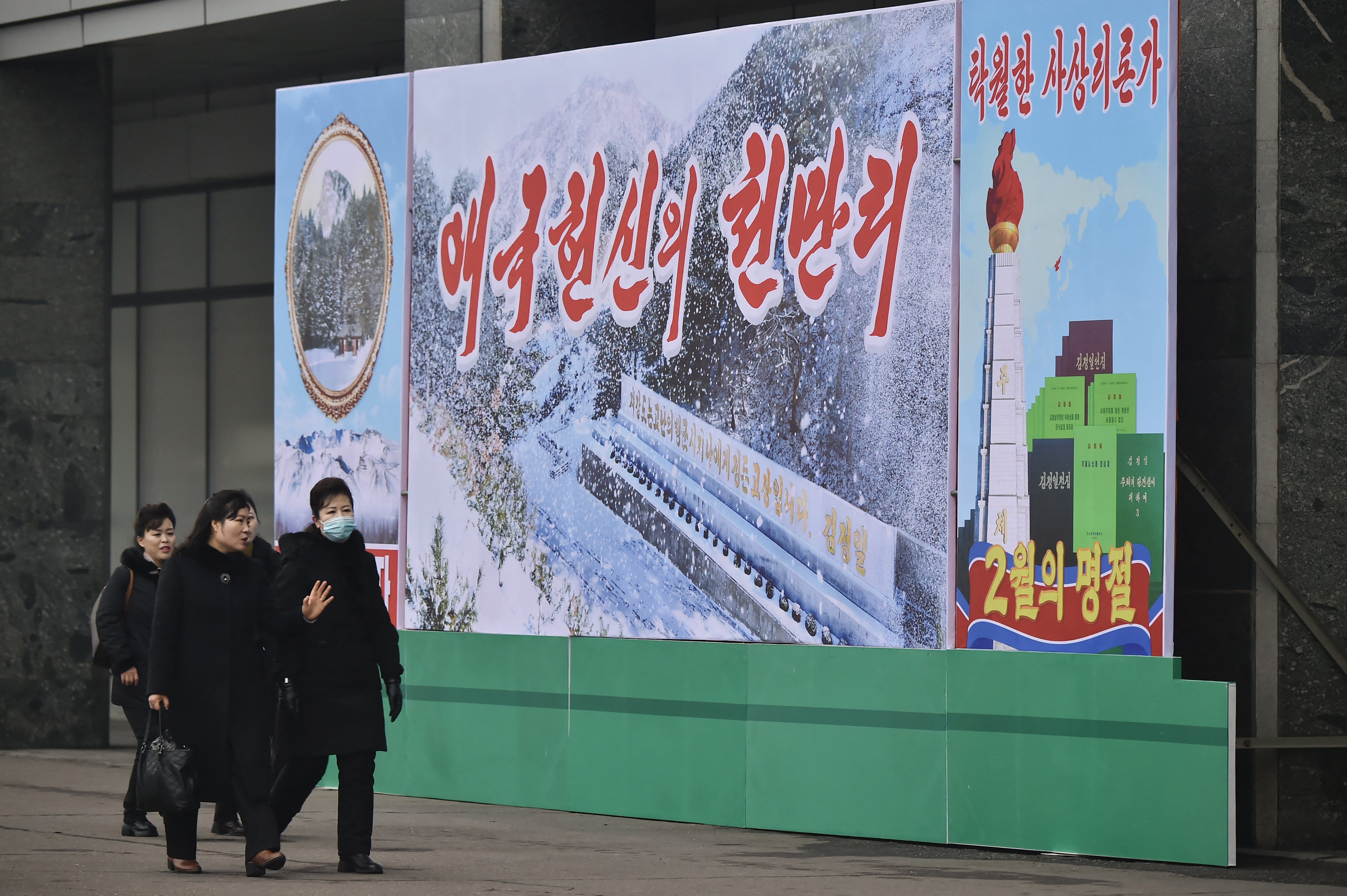 People walk on a street outside Pyongyang Department Store No. 1 near a celebrative poster displayed to mark the occasion of the 83rd birth anniversary of late North Korean leader Kim Jong Il in Pyongyang on February 16, 2025