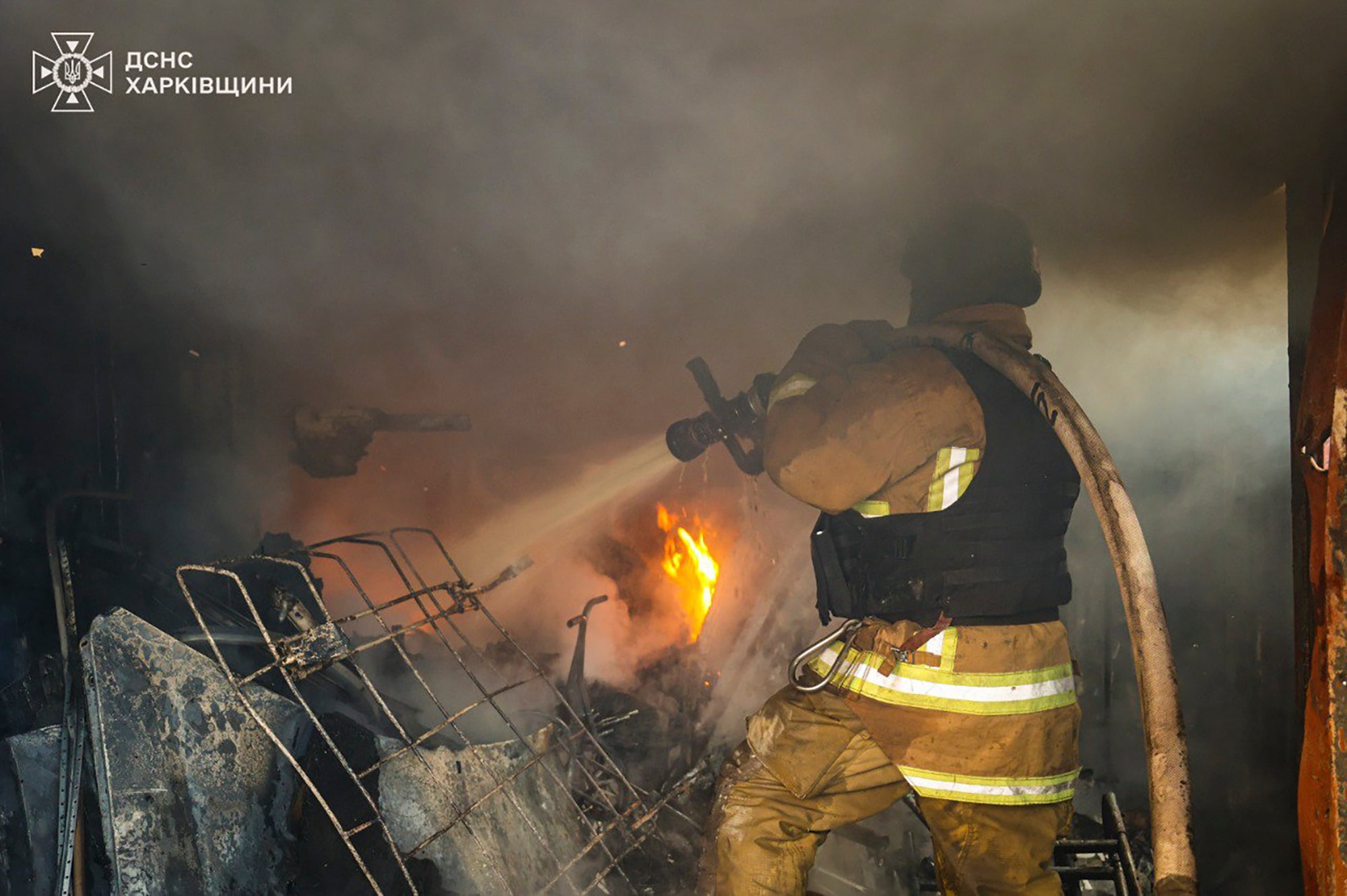 In this photo provided by the Ukrainian Emergency Service, a firefighter works to extinguish the fire following a Russian rocket attack in Kharkiv