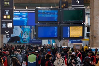Passengers stand under an information screen displaying that traffic has been stopped at the Gare du Nord station in Paris