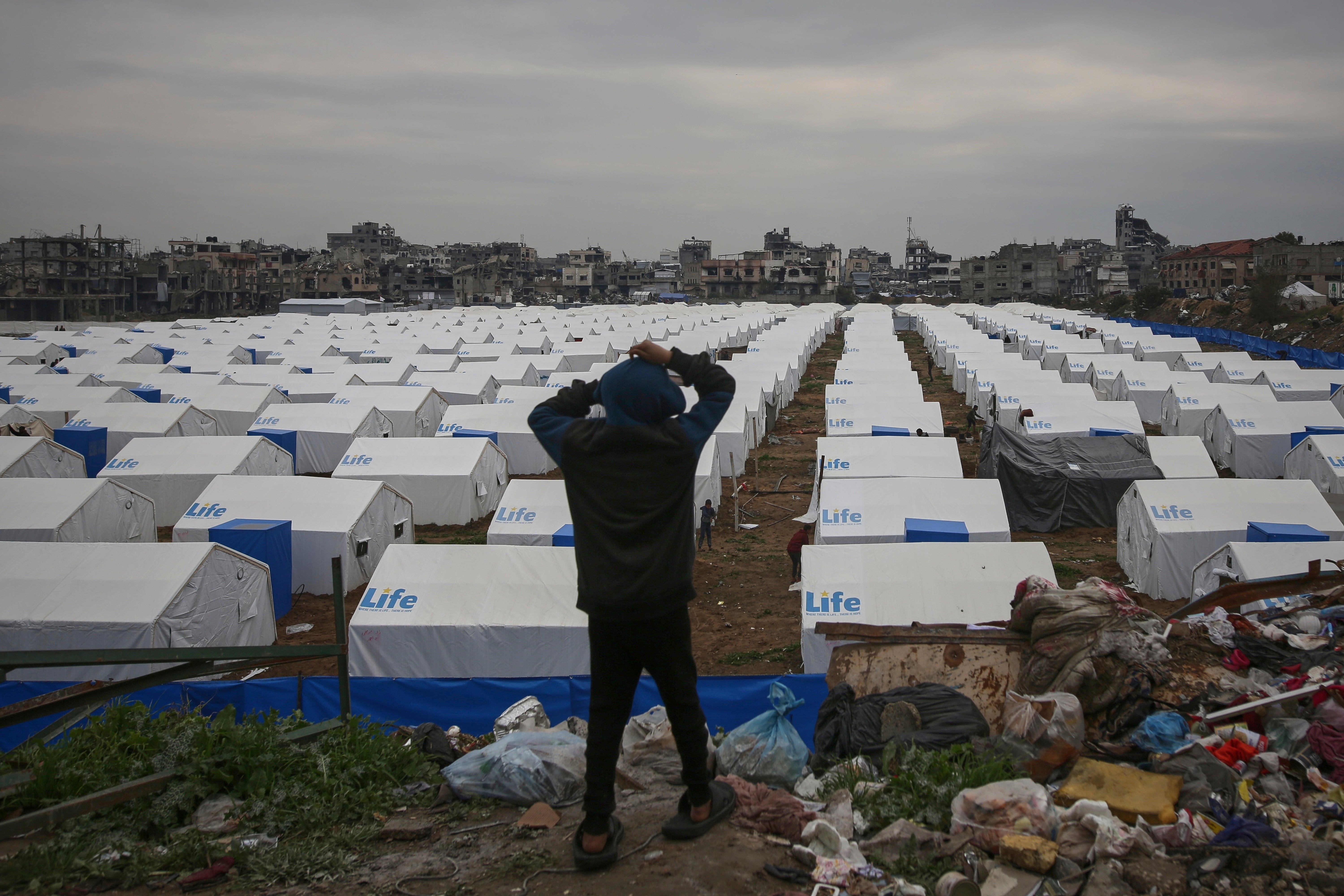 A boy looks over a newly established tent camp for displaced Palestinians in Gaza city