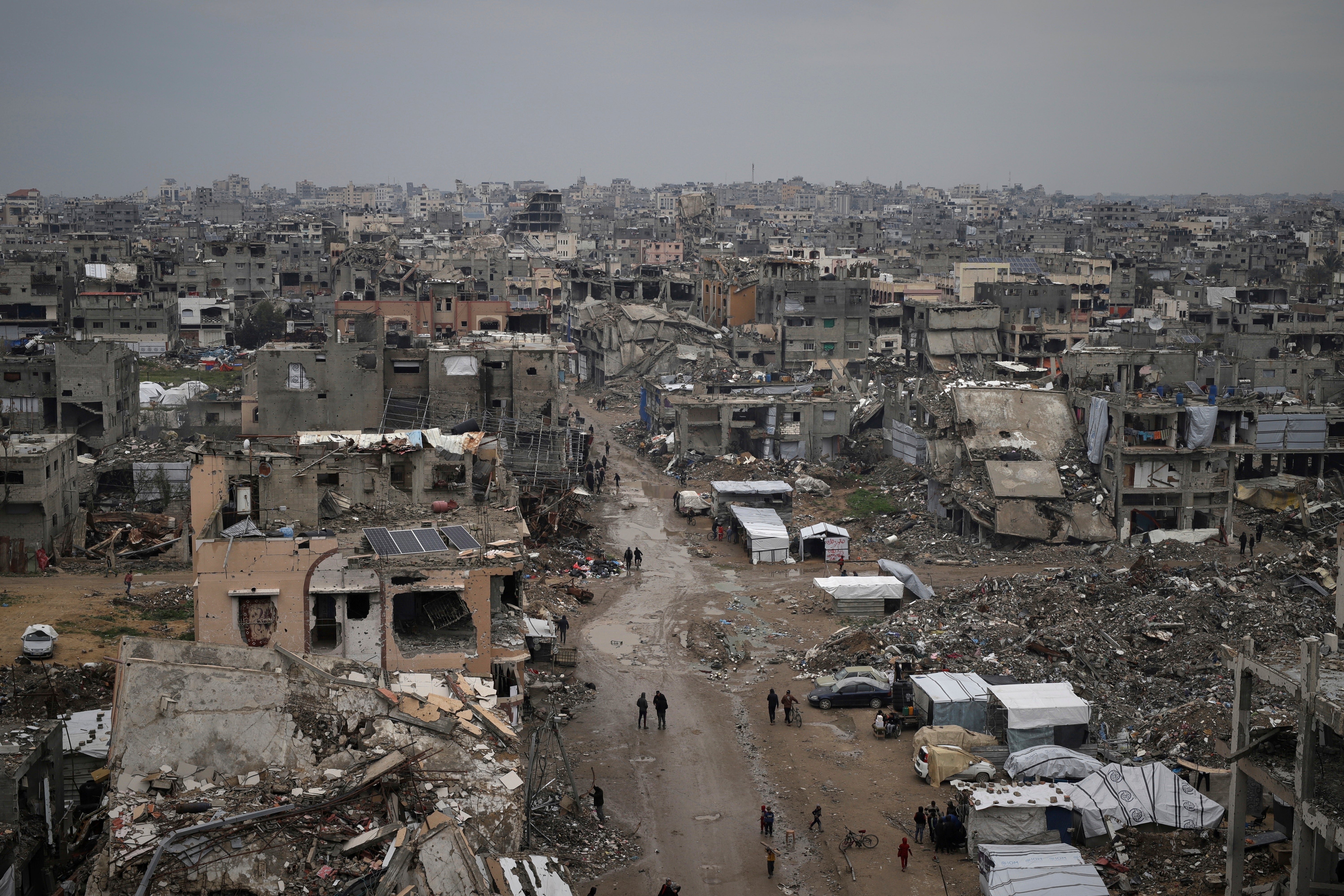 Palestinians walk through the rubble of destroyed neighbourhoods