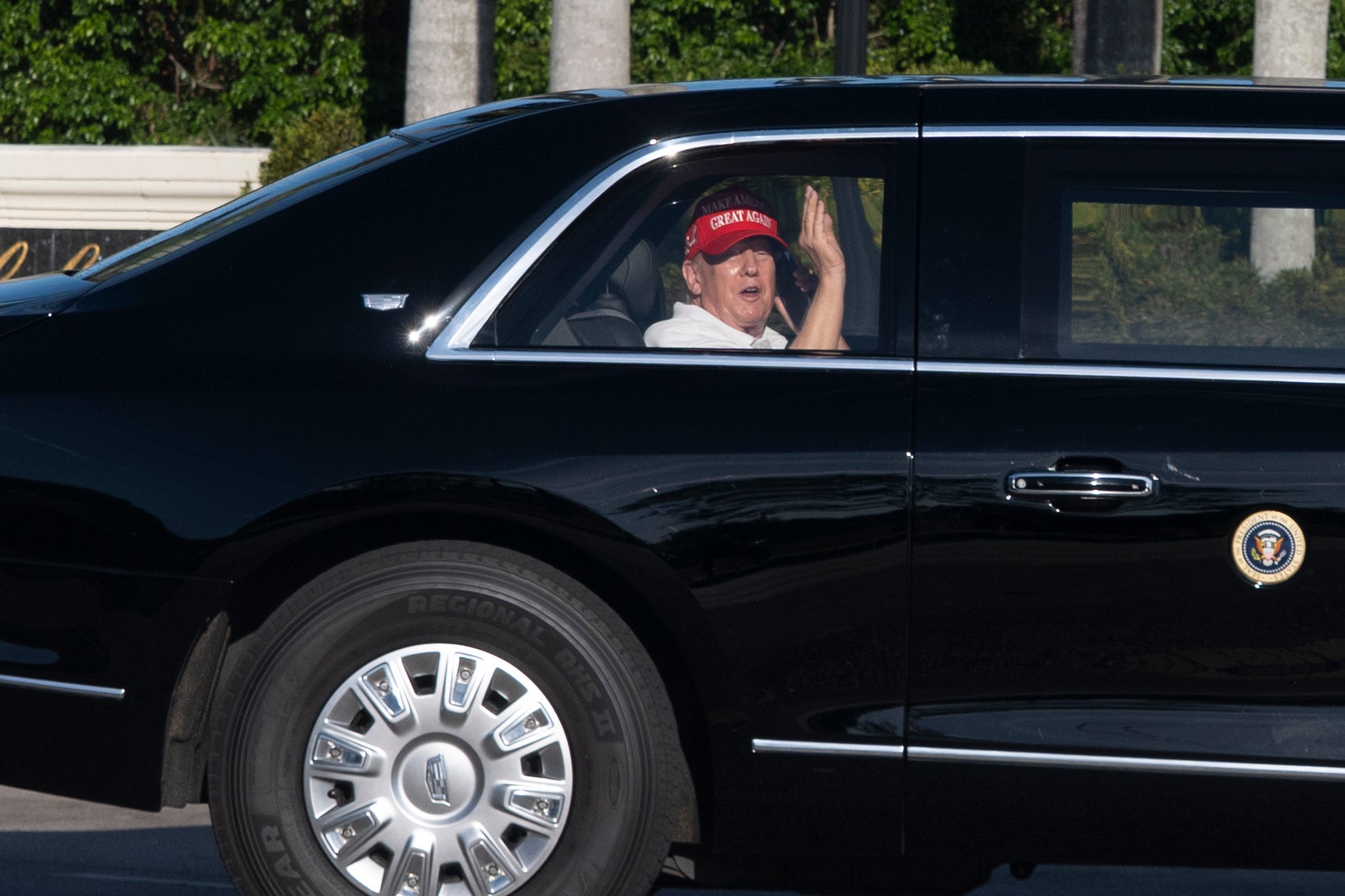 President Donald Trump waves from his limousine as he arrives at his golf club in West Palm Beach on March 8, 2025