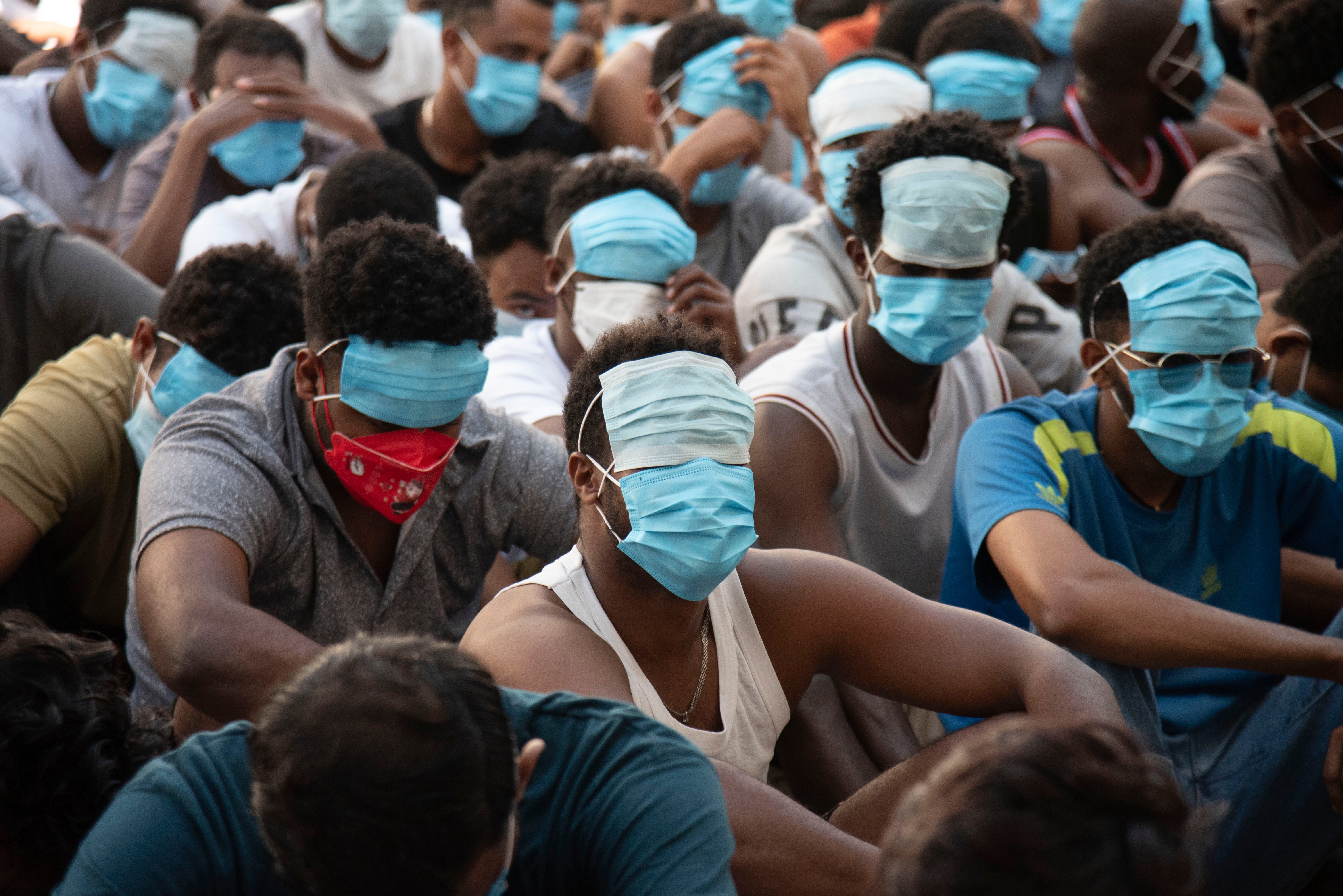 People from China, Vietnam and Ethiopia sit with their faces masked while in detention