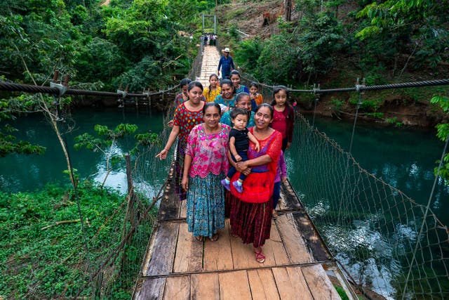 Women from the La Paz community in central Guatemala cross a bridge built to get them across the river. (Brian Lawless/PA)