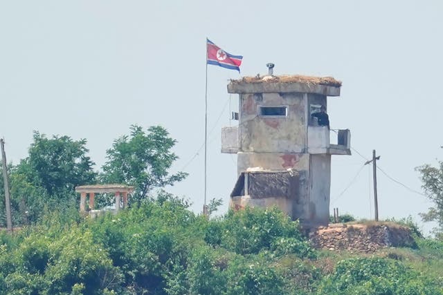 <p>Soldier stands at a North Korean military guard post flying a national flag, seen from Paju, South Korea</p>