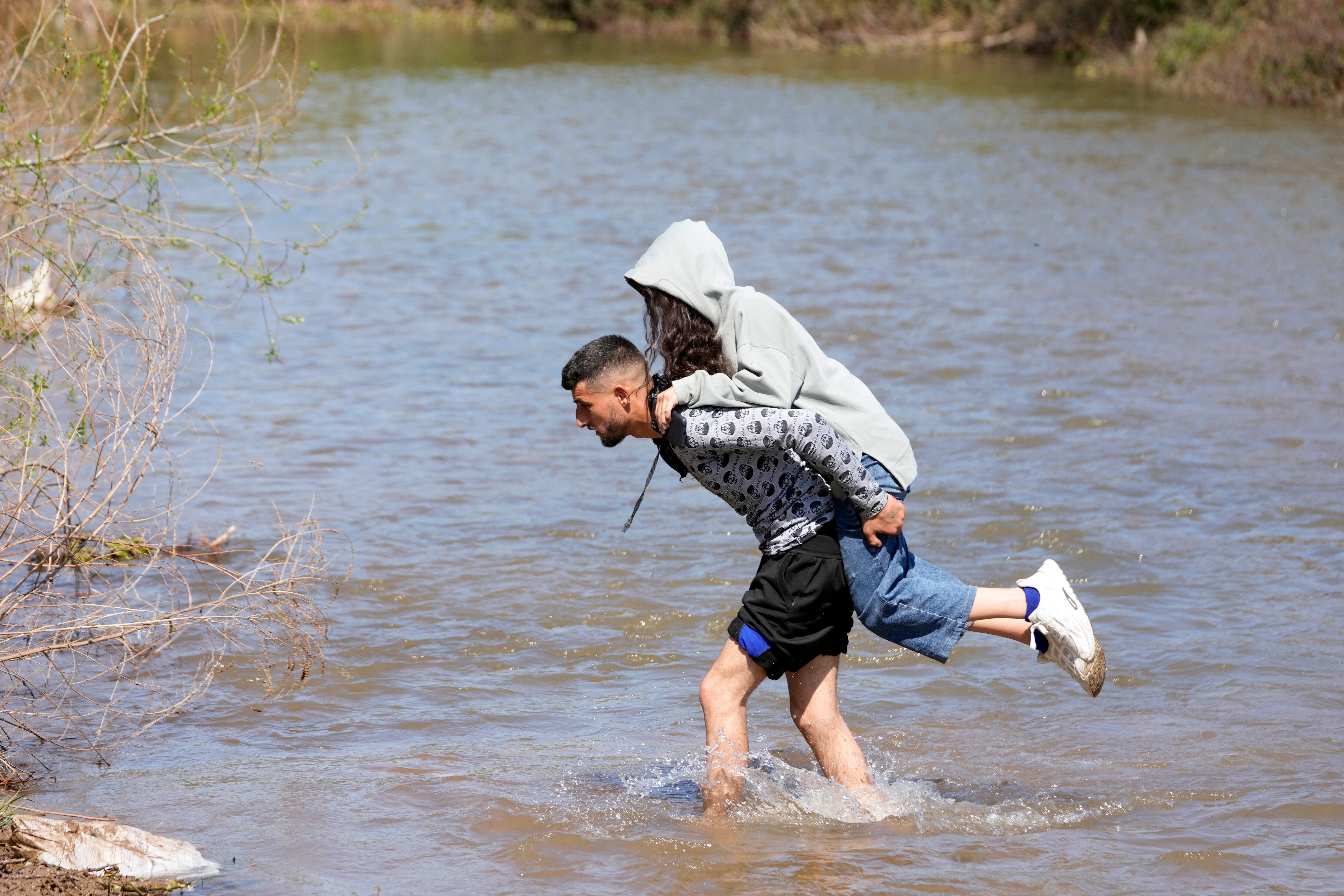 Syrian families who fled the clashes in Syria cross a river marking the border between Syria and northern Lebanon in Heker al-Daher village