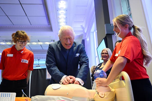 The King refreshed his first aid skills when he practised resuscitating a dummy patient under the watchful eye of nursing cadets (Jaimi Joy/PA)