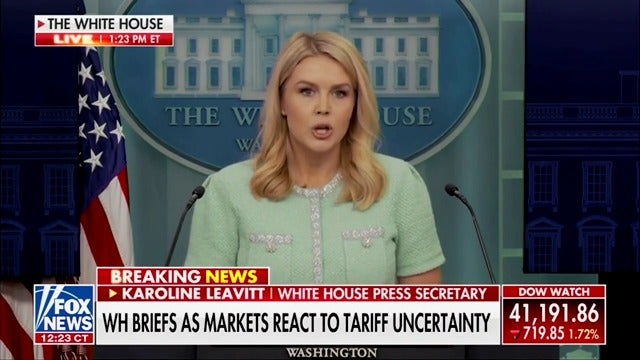 White House press secretary Karoline Leavitt brags that Trump's "America First" policies will boost the economy, all while the Dow Jones sinks in real-time during Fox News' live broadcast of her remarks.