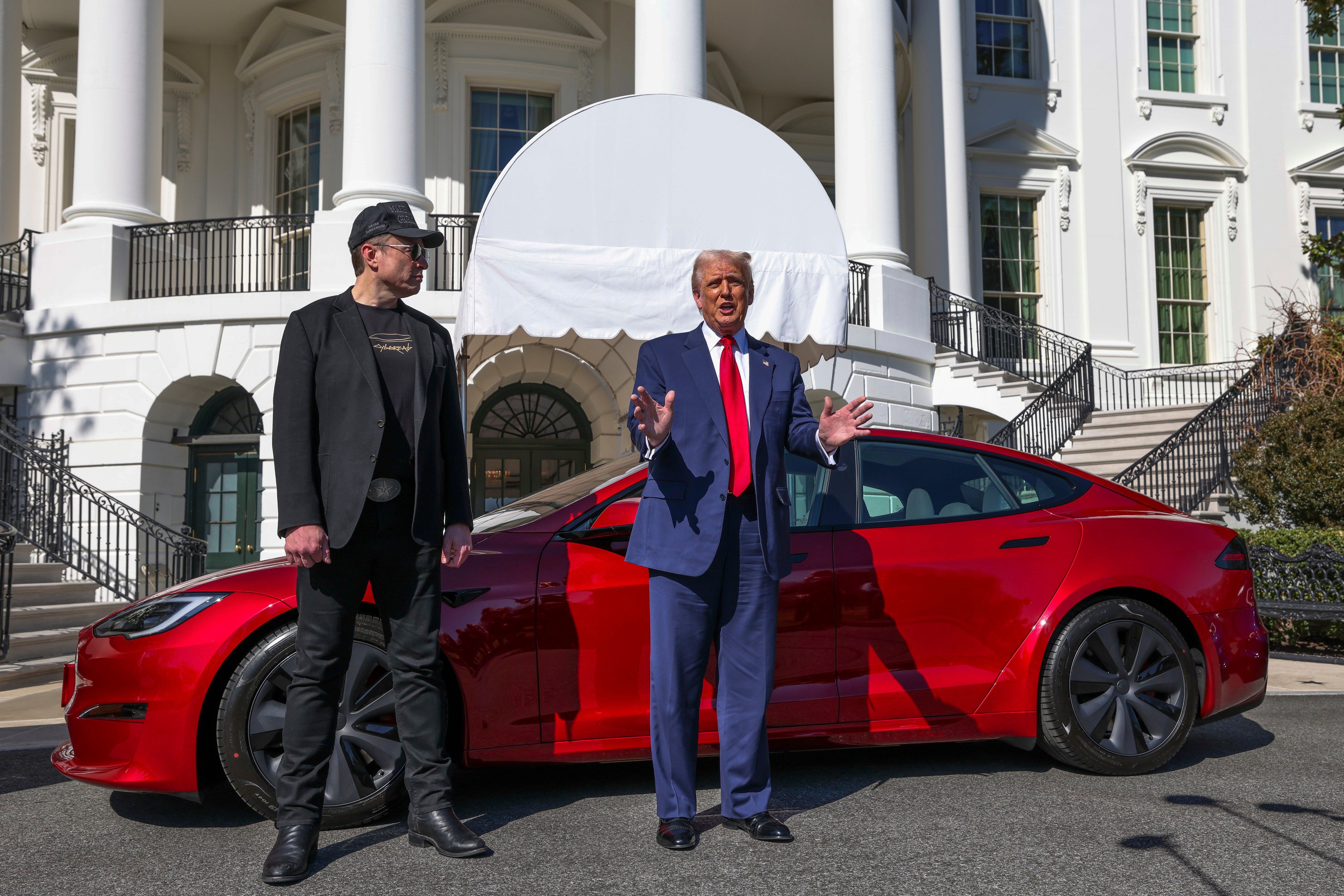 President Donald Trump promotes a Tesla car from the White House’s south lawn alongside Elon Musk