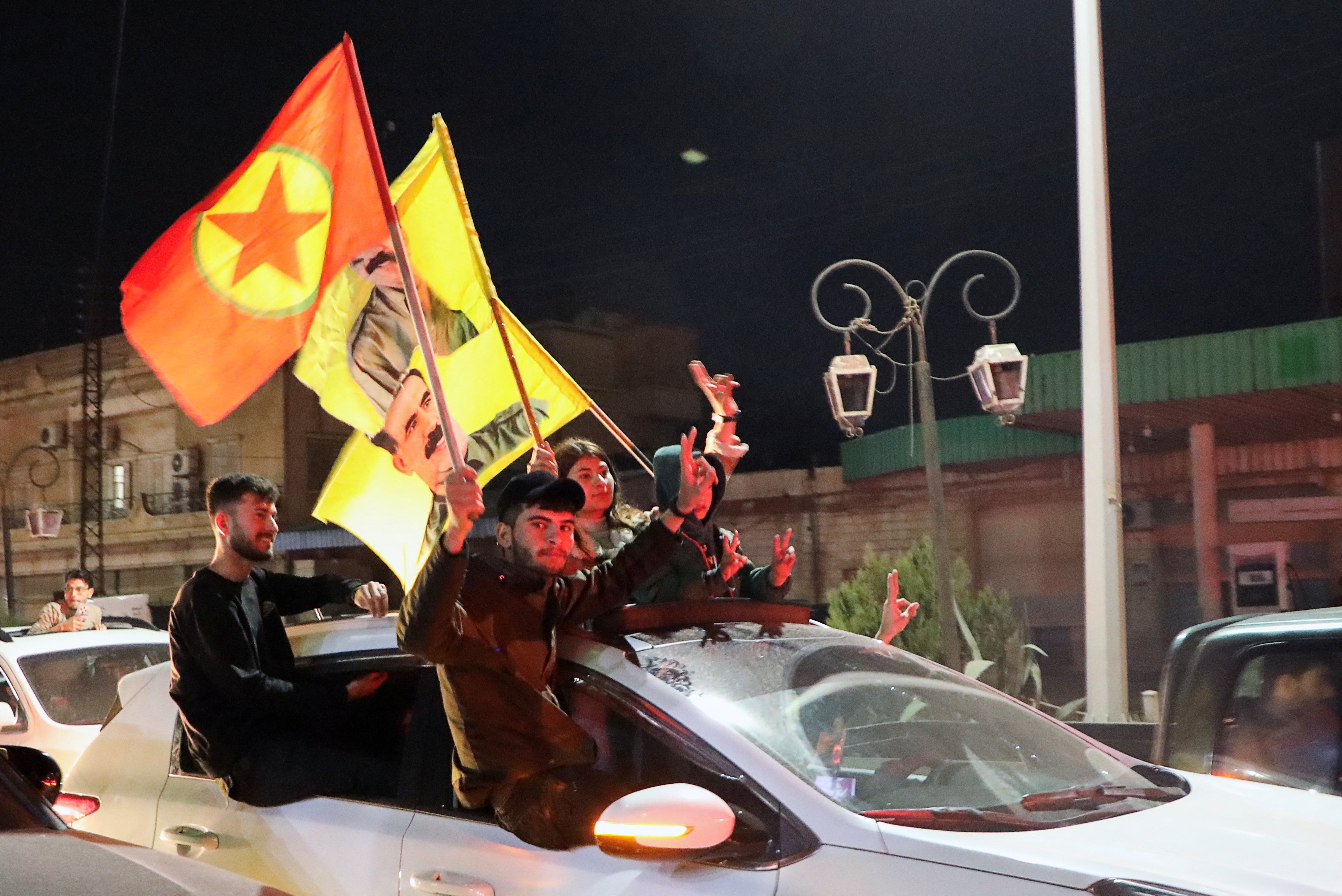 People hold Kurdistan Workers Party flag and pictures of its jailed leader Abdullah Ocalan as they celebrate the signing of the deal, in Qamishli, Syria, on 11 March 2025