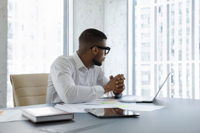 <p>This is a photo of a man sat at his desk at work staring out of a window</p>