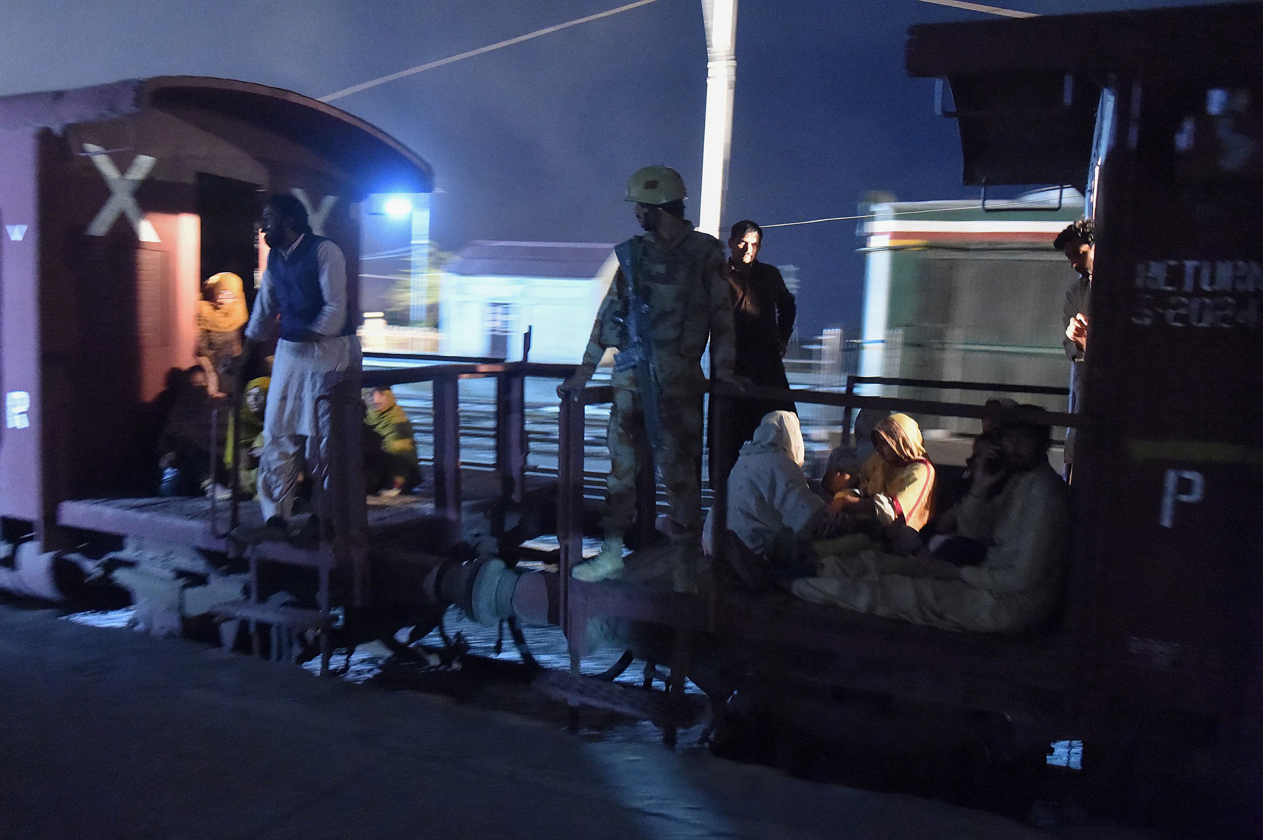 A soldier helps evacuate freed passengers at Mach railway station, which has been turned into a makeshift hospital