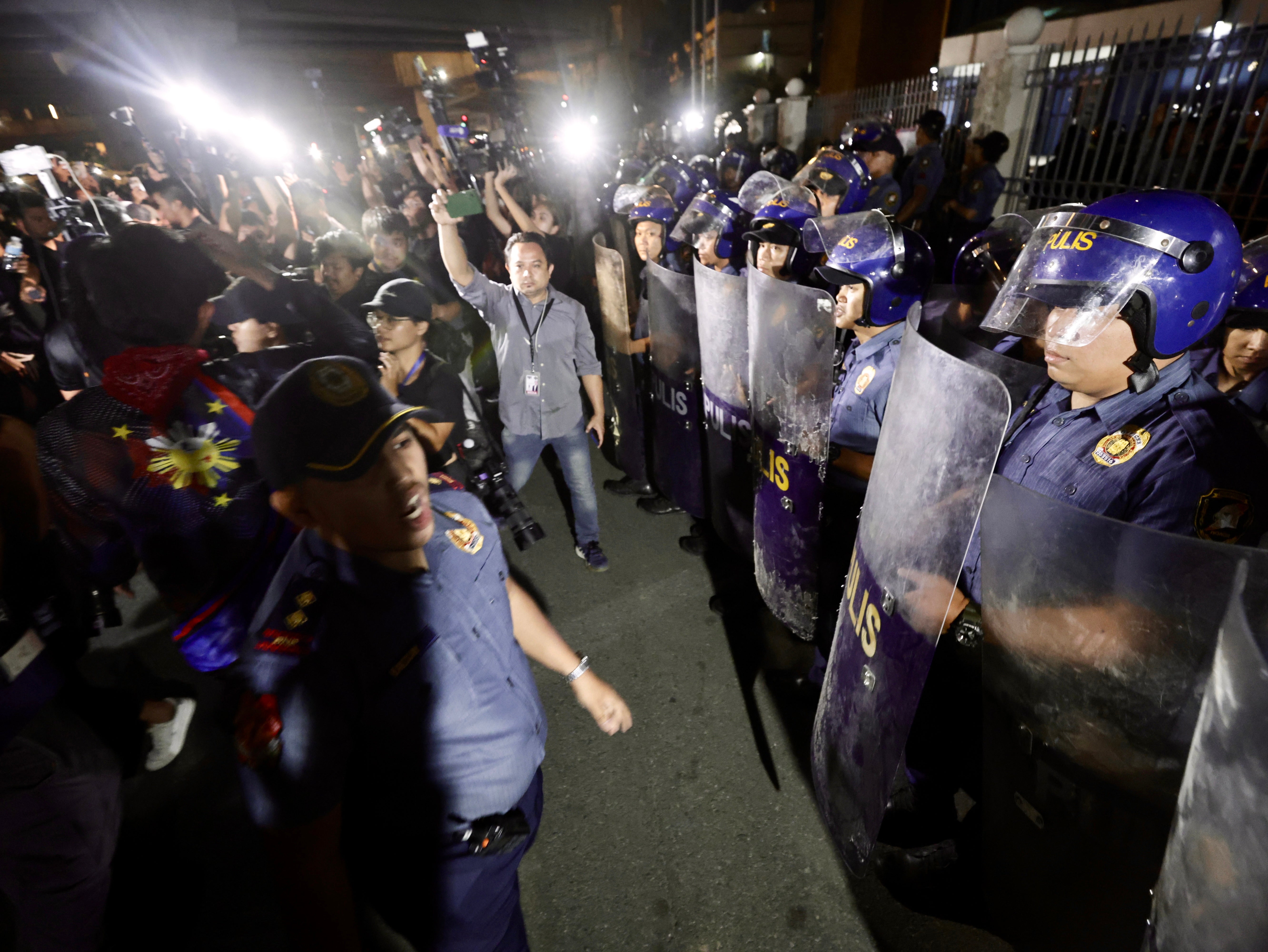 Anti-riot police stand in formation at the gates of a military airbase where former president Rodrigo Duterte is being detained in Manila