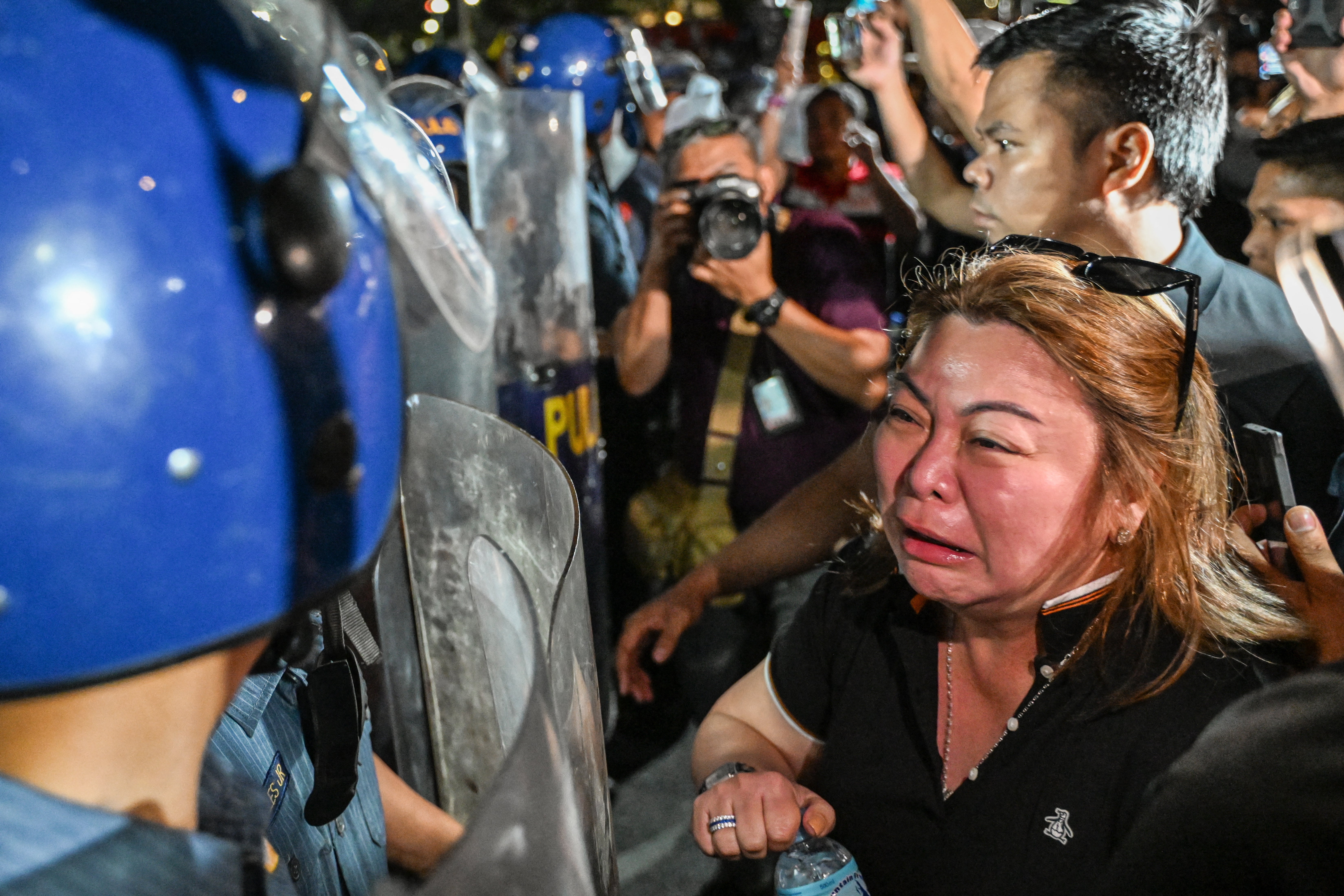 A supporter of former Philippine president Rodrigo Duterte reacts while facing police outside Villamor Air Base, where he is currently being held according to his political party, in Pasay, Metro Manila