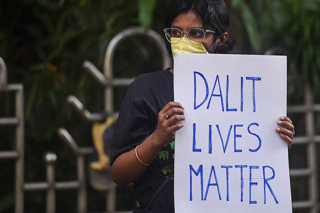 <p>An activist holds a placard during a protest to condemn caste-based violence</p>