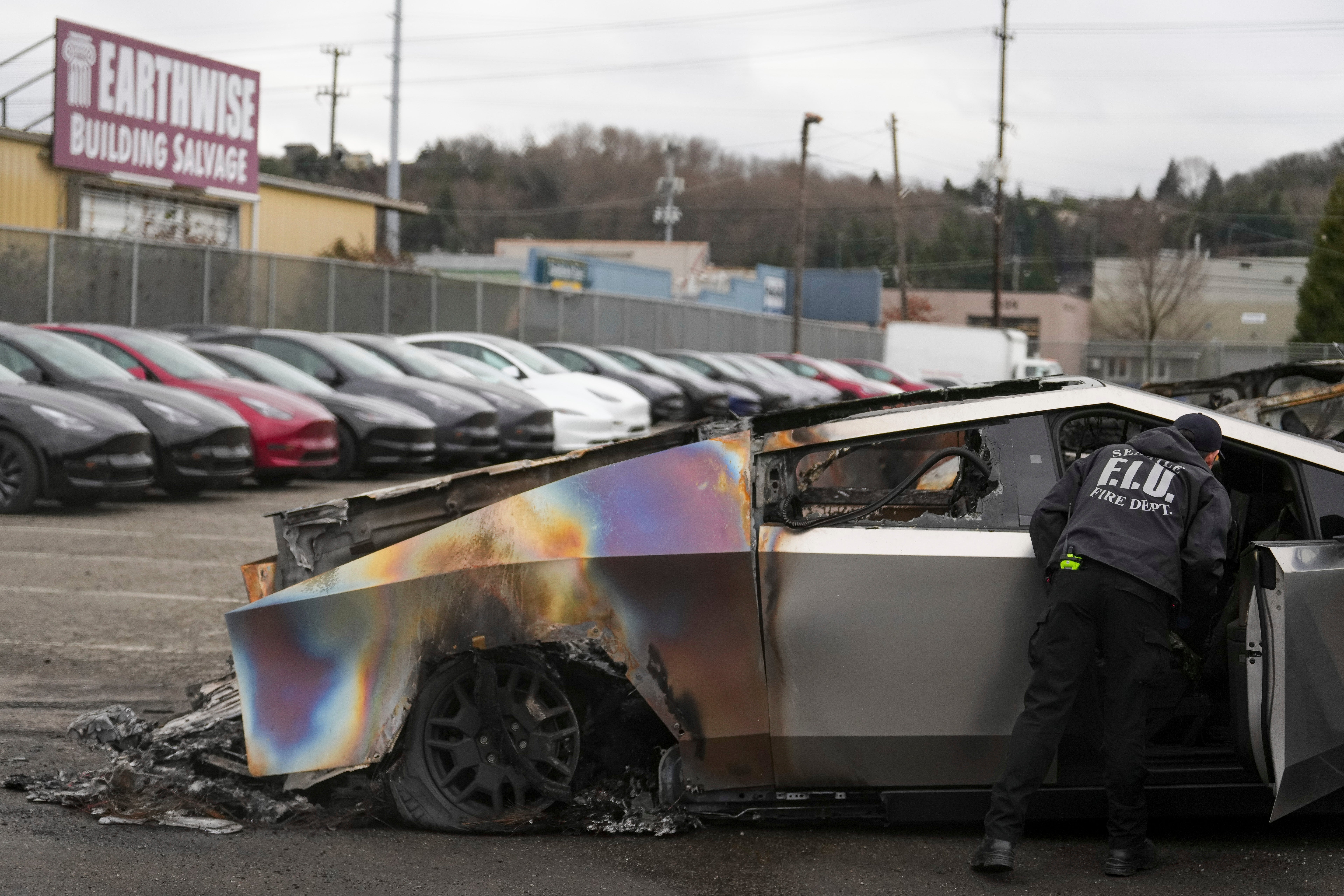 A member of the Seattle Fire Department inspects a burned Tesla Cybertruck at a Tesla lot in Seattle