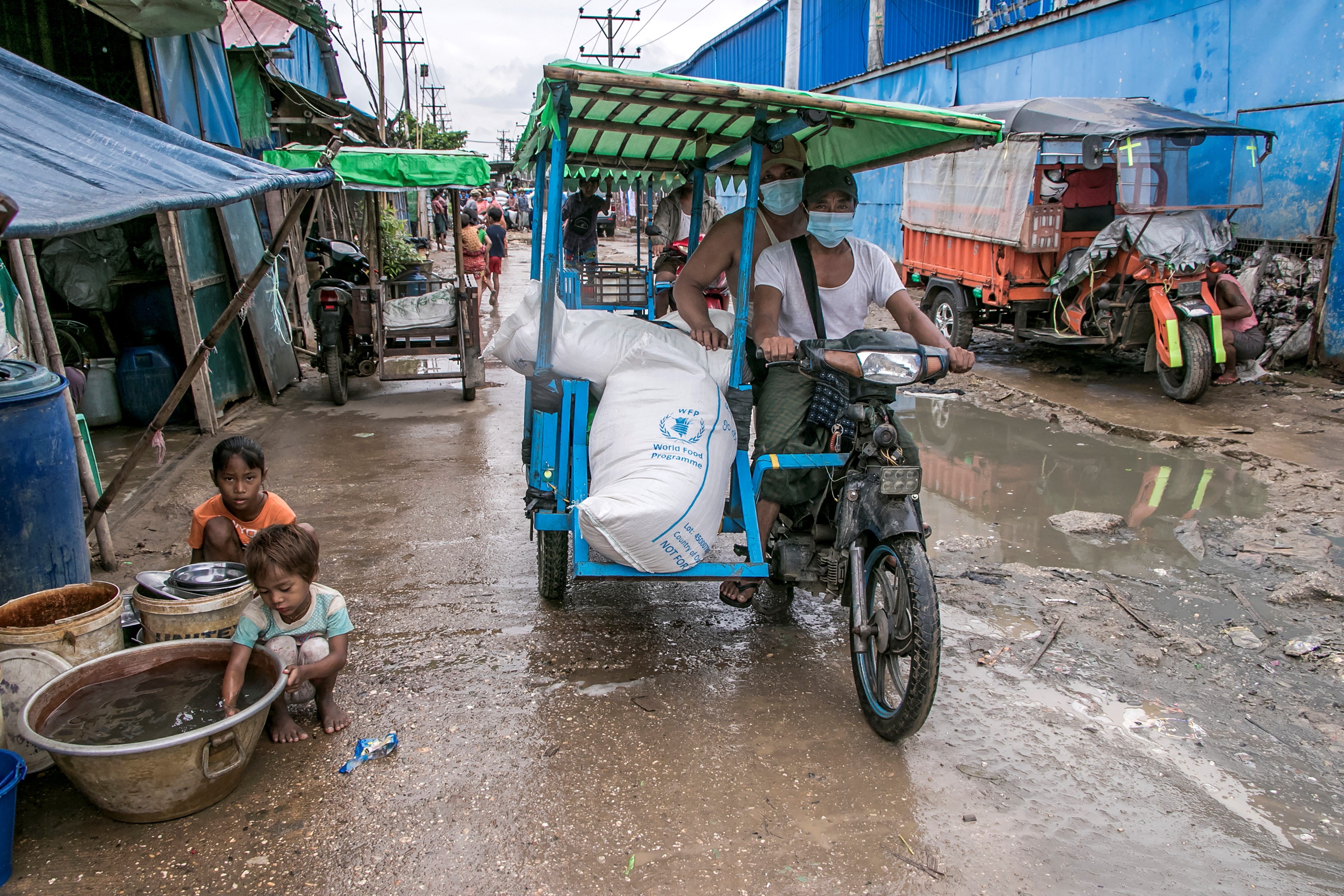 Men transport bags of rice distributed by the World Food Programme as part of aid efforts to support residents living in poor communities on the outskirts of Yangon