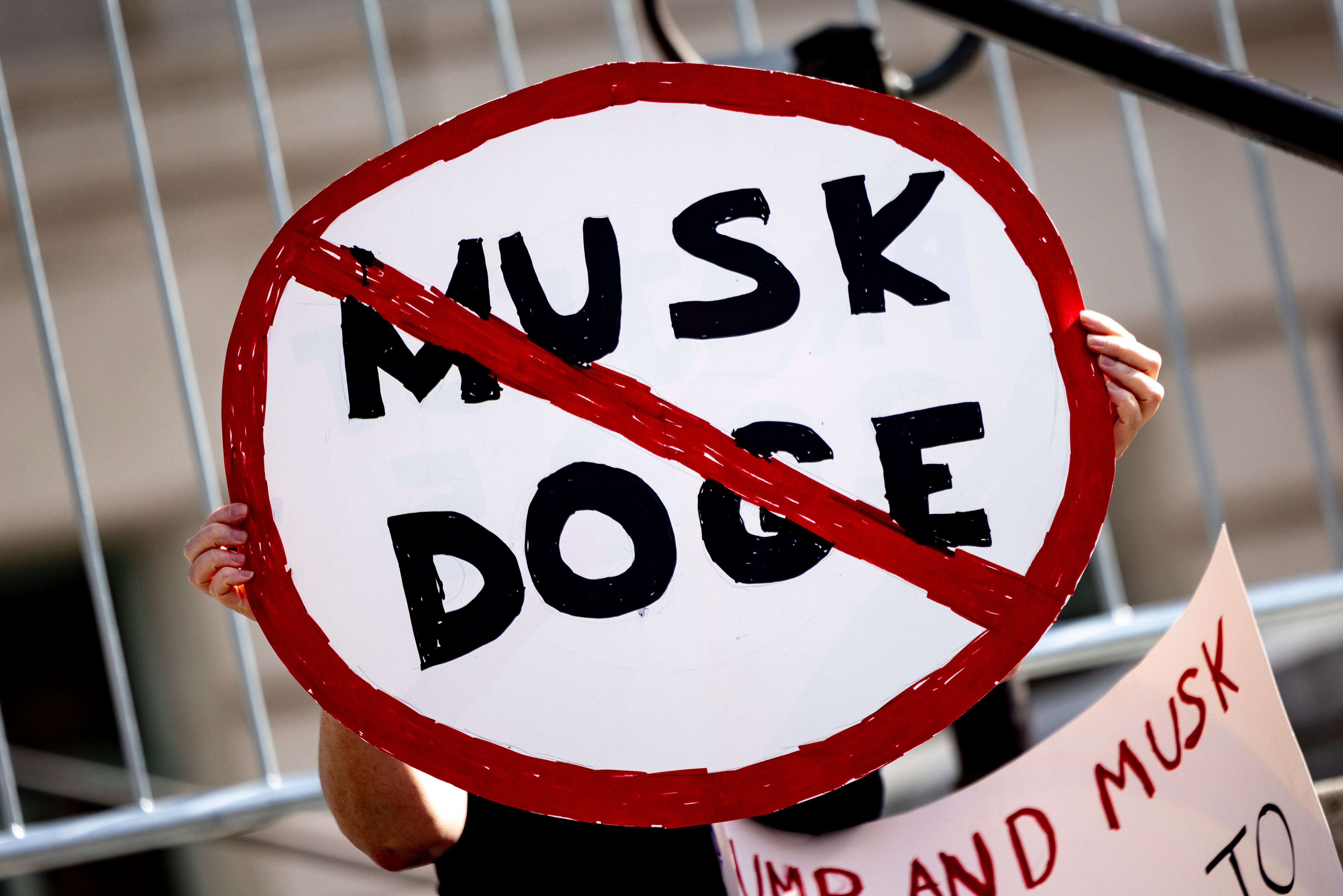 A demonstrator holds a sign as they protest Musk’s DOGE