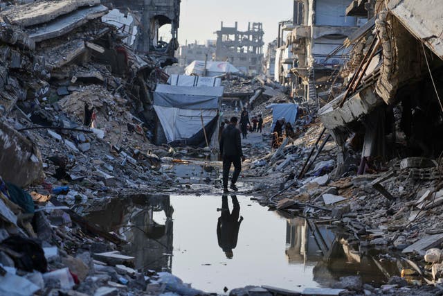 <p>Palestinians walk amid the rubble of destroyed homes and buildings in Jabaliya, northern Gaza, on Friday</p>