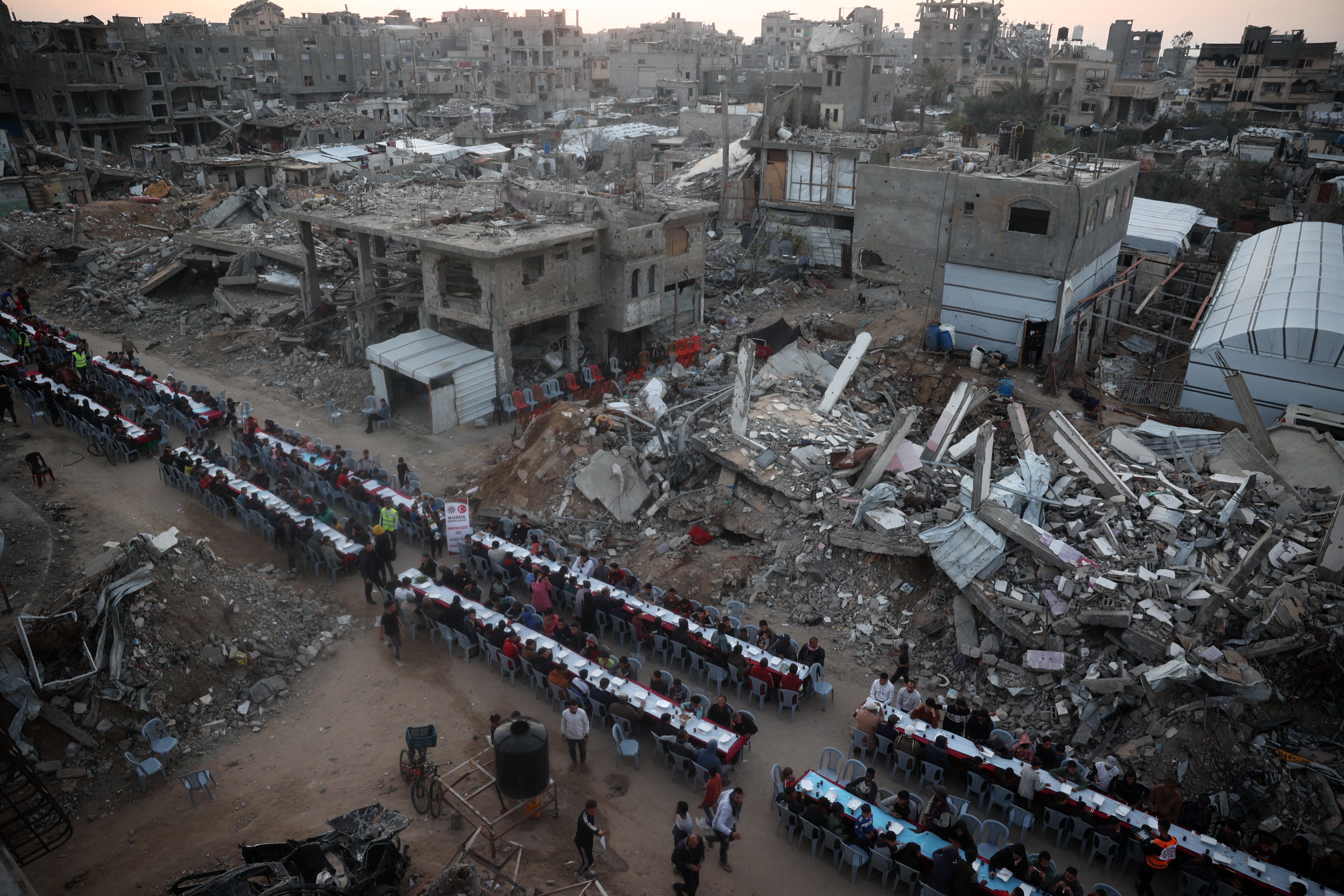 The Palestinians gather for a common Iftar meal to break their fasting in the middle of devastation in the Nuseirat refugee camp in the Central Gaza Strip Friday