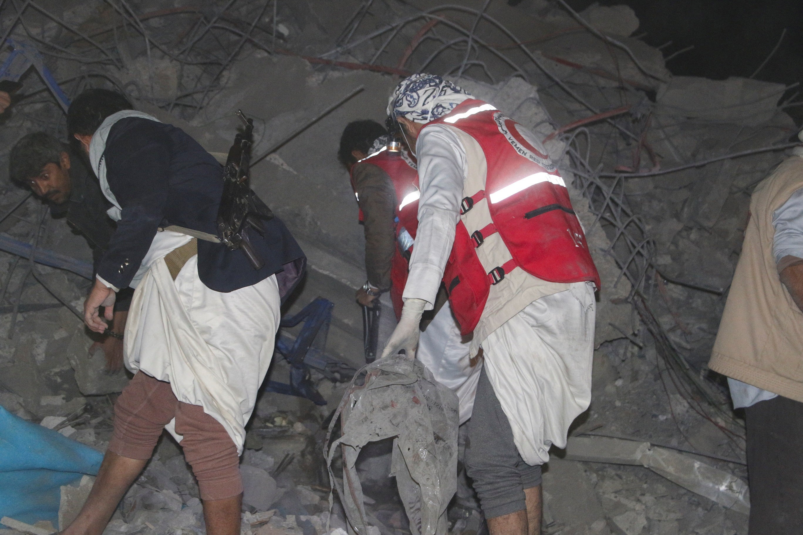 People and rescuers search through the rubble of a house hit by a US strike in Yemen