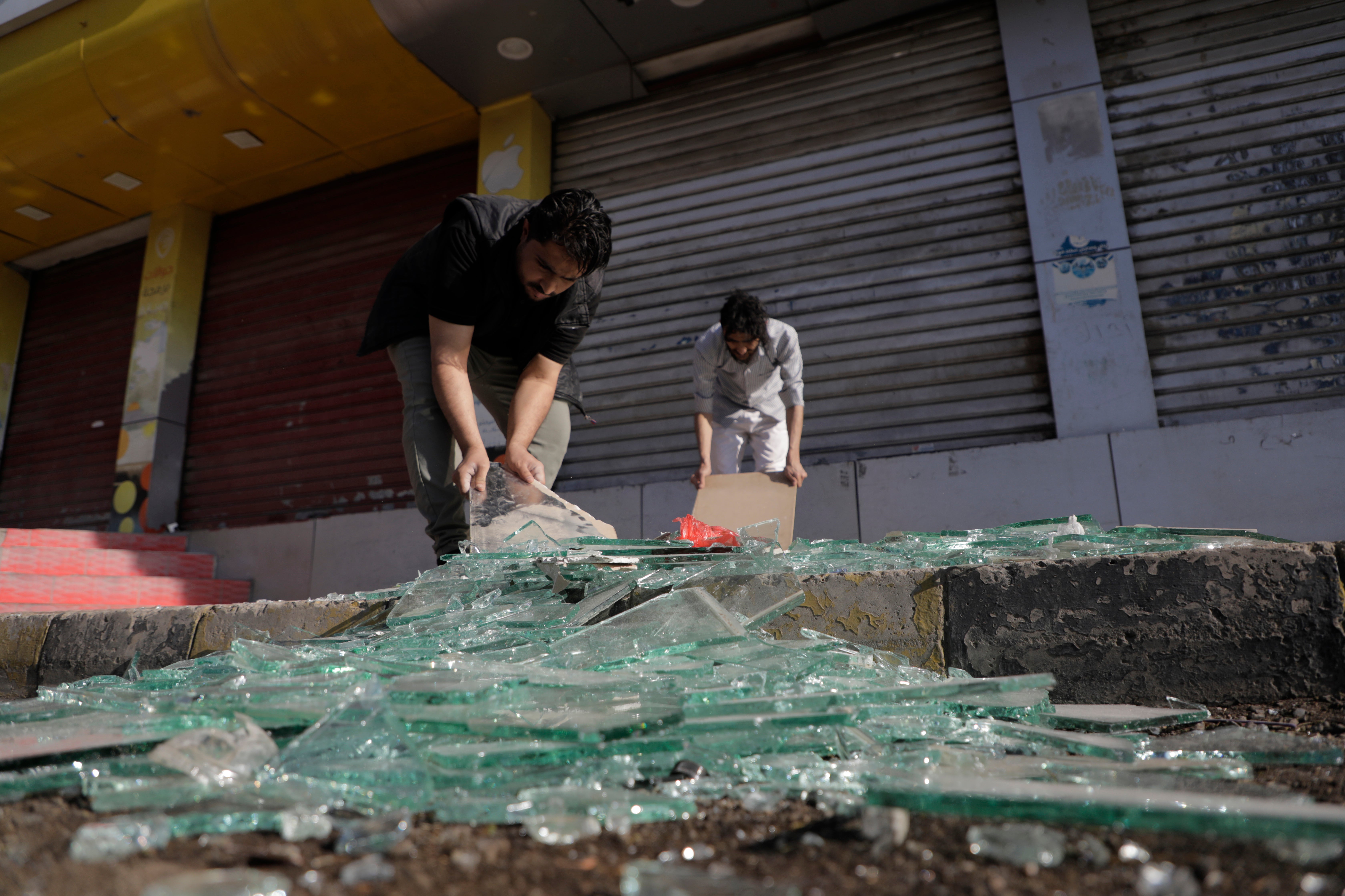 Yemenis clean debris in front of their shops after a US airstrikes in Sanaa, Yemen, on Sunday