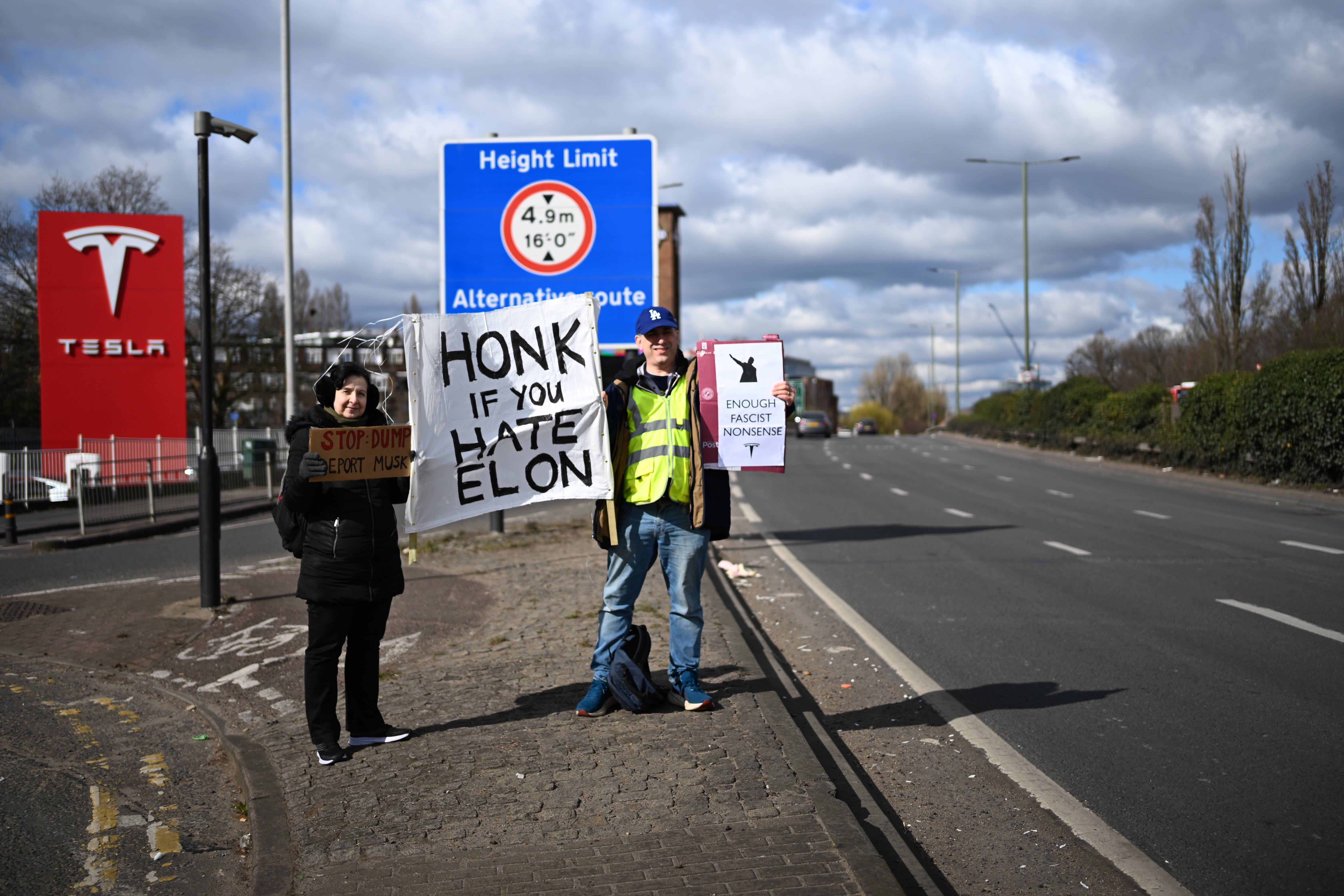 A ‘Honk if you hate Elon’ sign is held next to a busy A-road in west London on Saturday