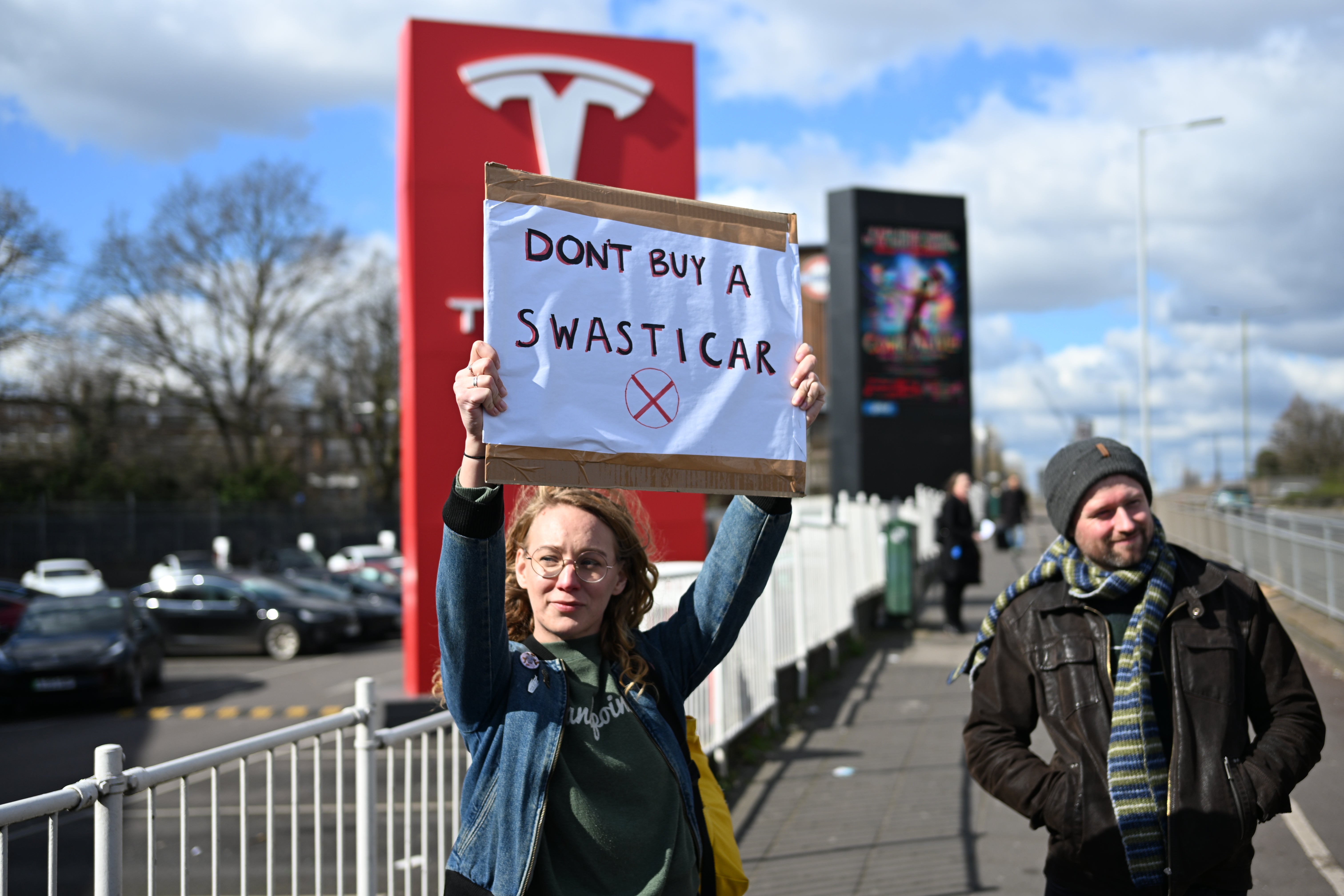 <p>‘Don’t by a Swasticar’, reads a placard outside a Tesla dealership in west London</p>