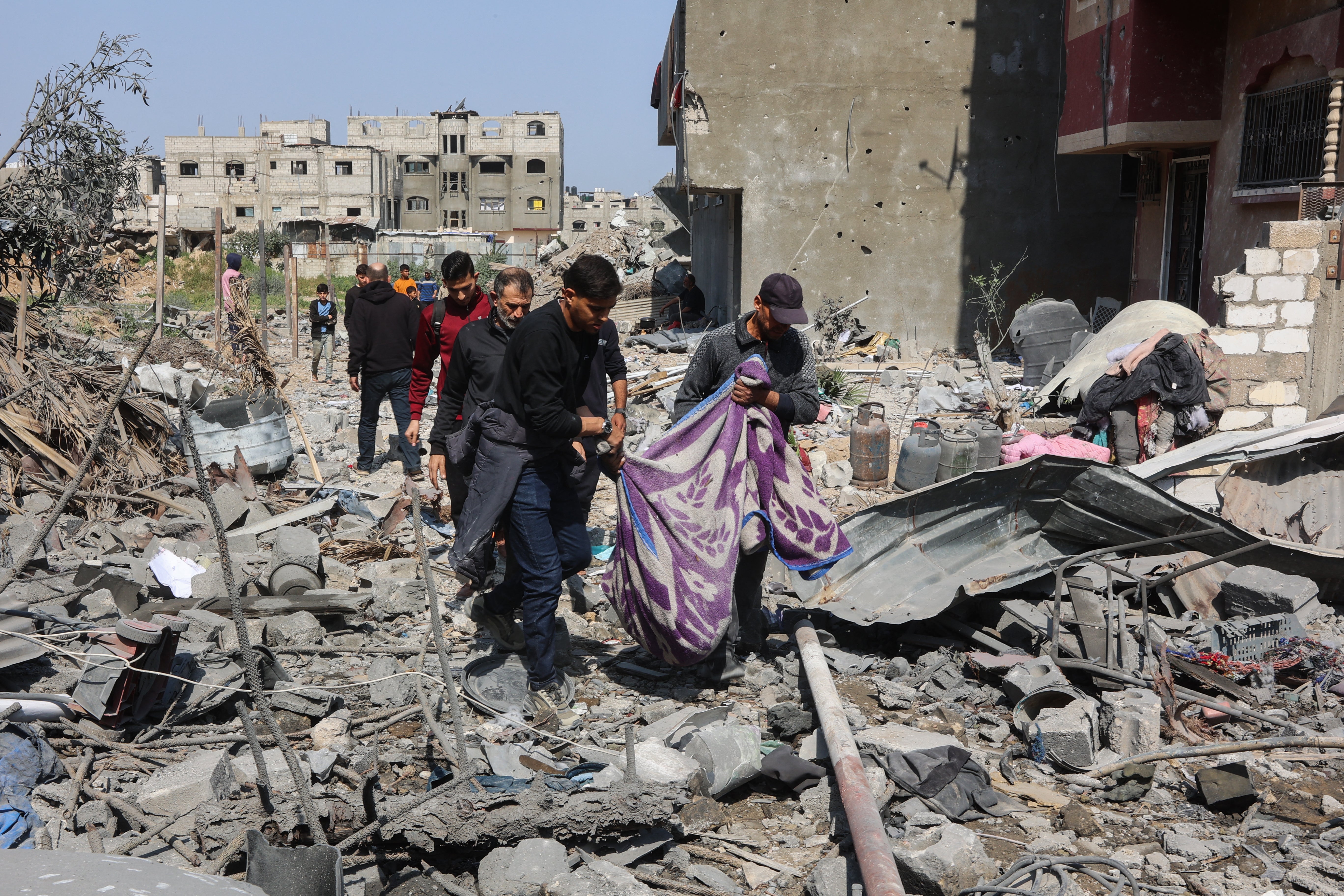 Palestinians carry a body pulled from the rubble of the Qrayqea family house, destroyed in Israeli strikes on 18 March 2025